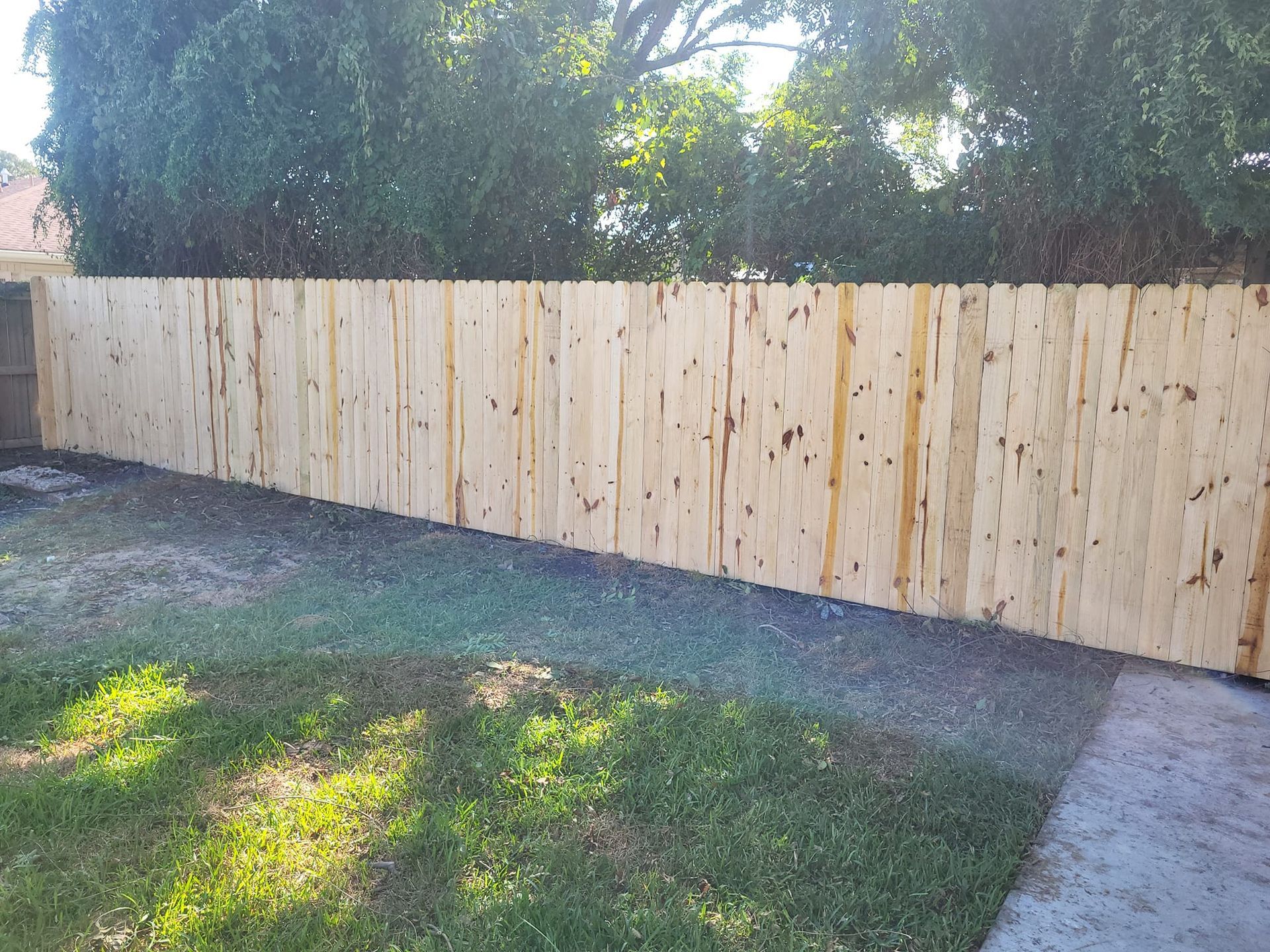 A wooden fence is in the backyard of a house.