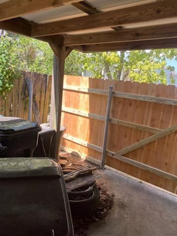 There is a wooden fence behind the trash cans.