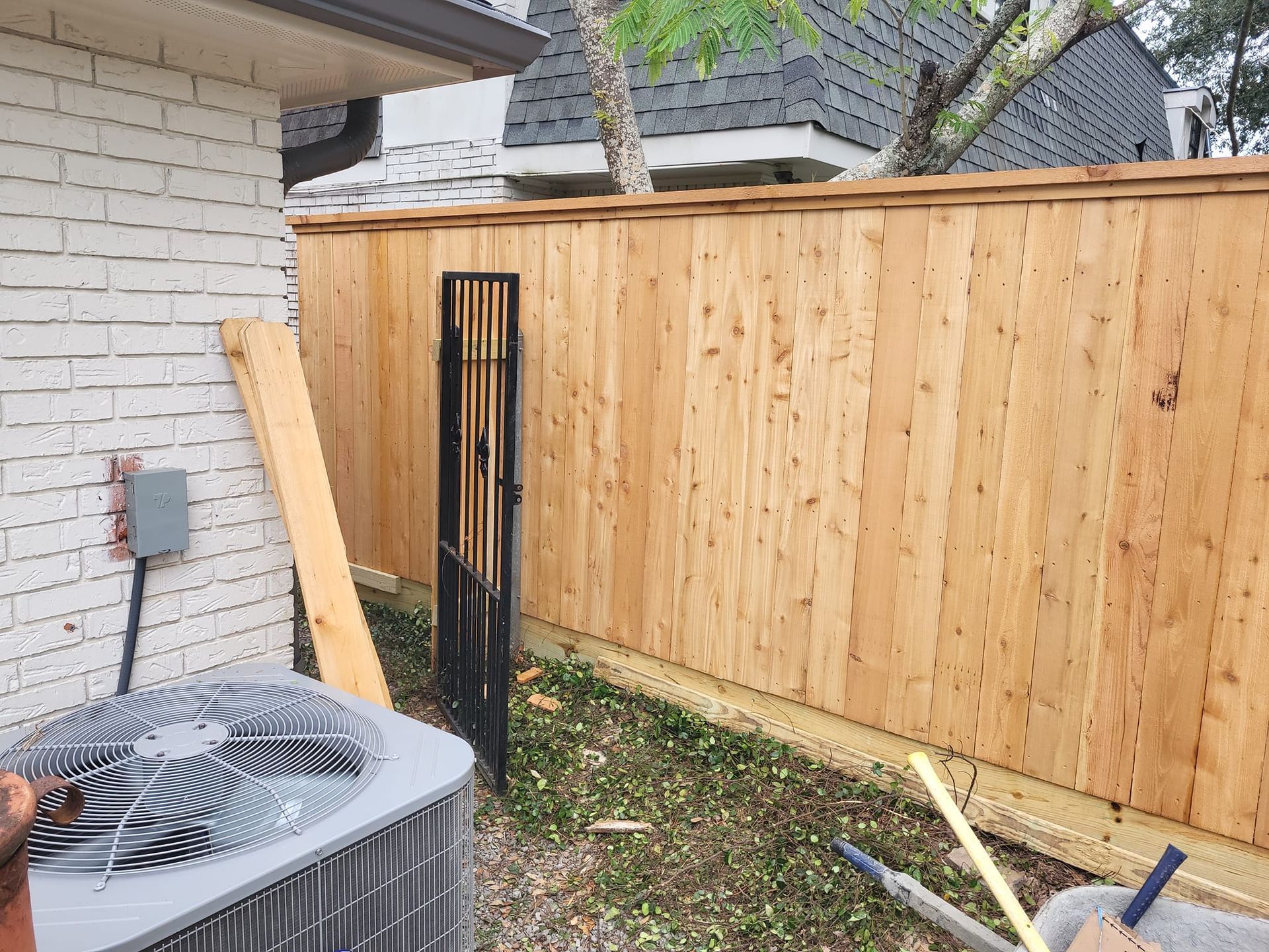 A wooden fence is being built in the backyard of a house.