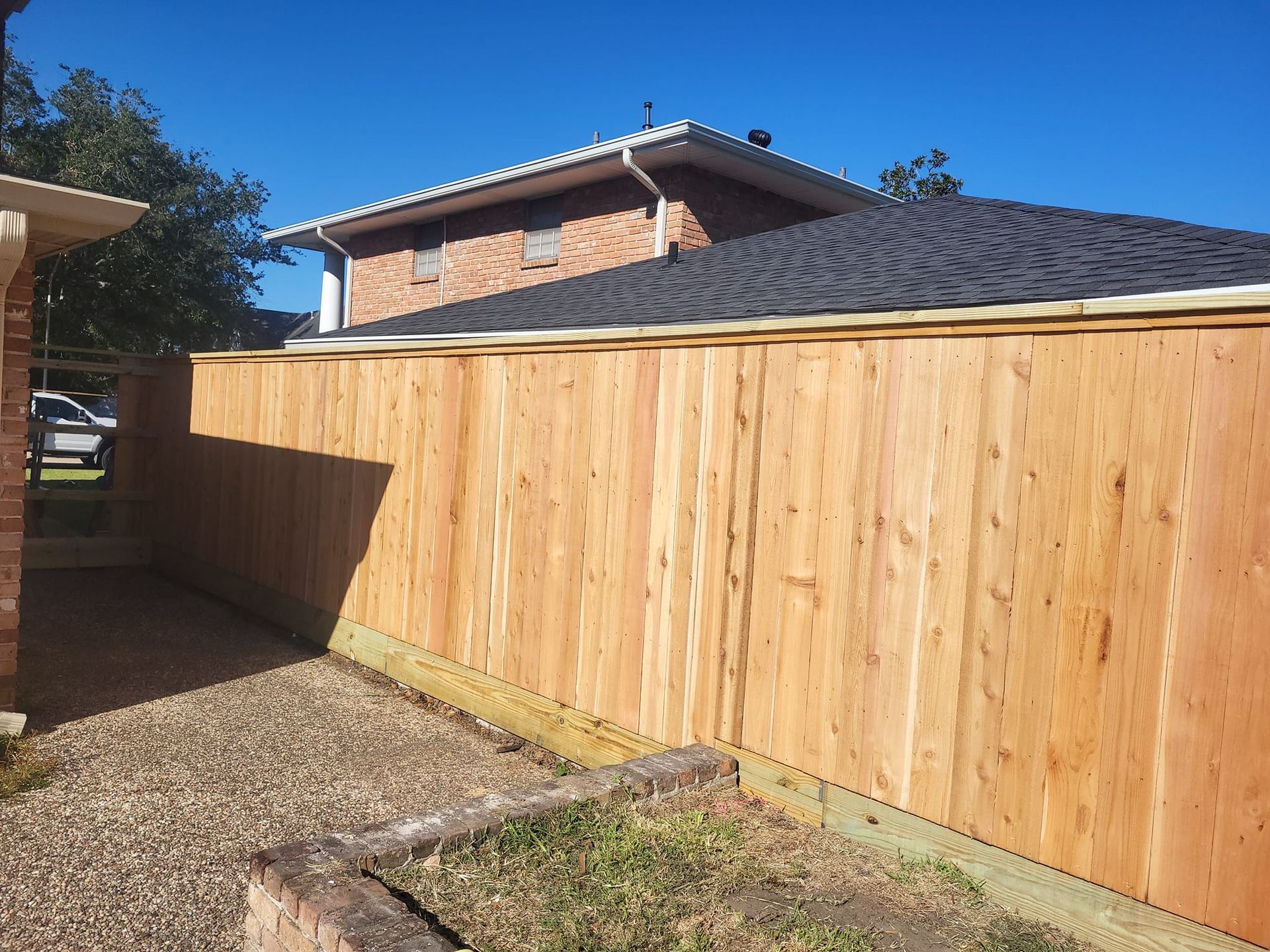 A wooden fence is in front of a brick house.