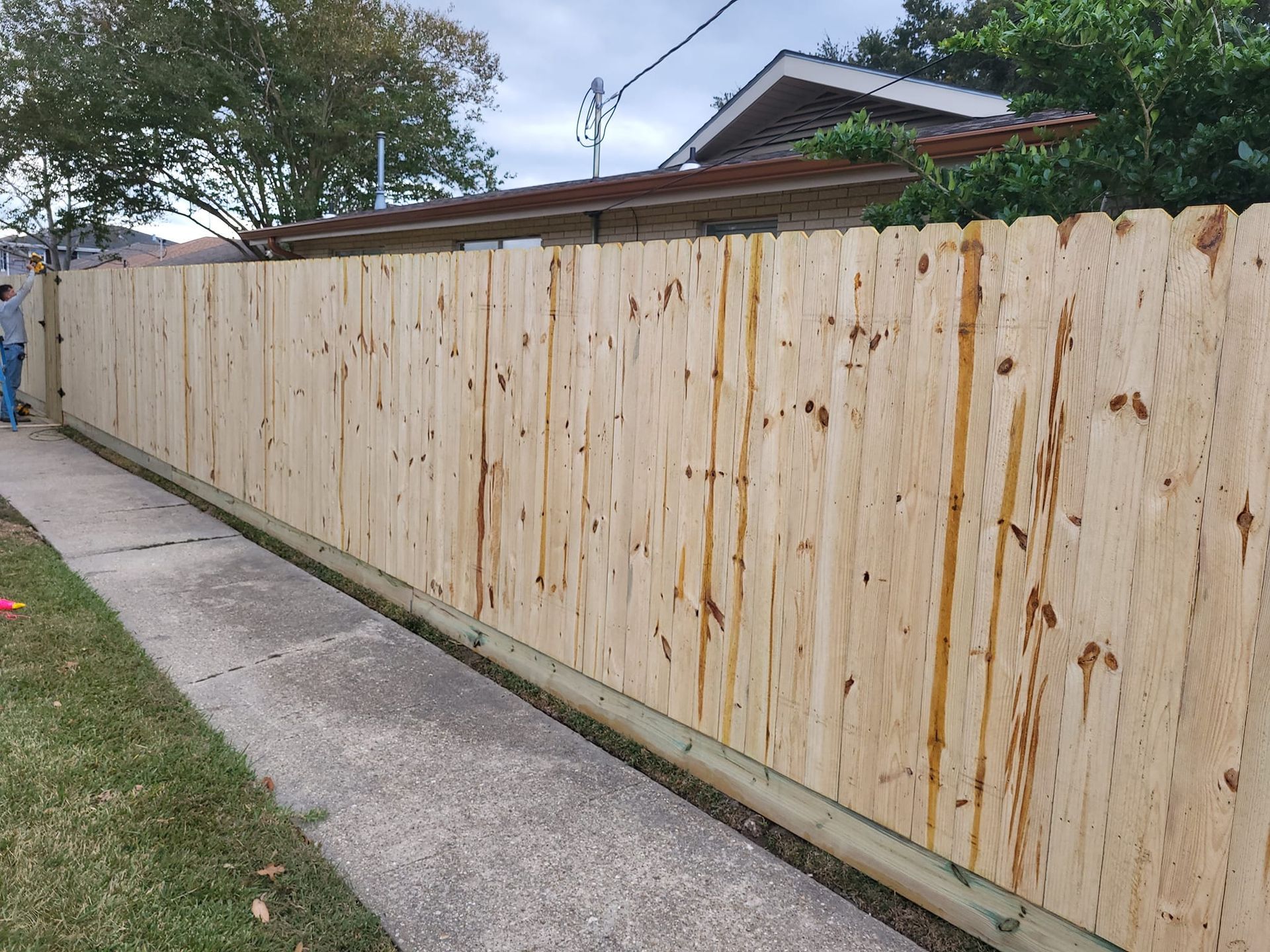 A wooden fence along a sidewalk next to a house.