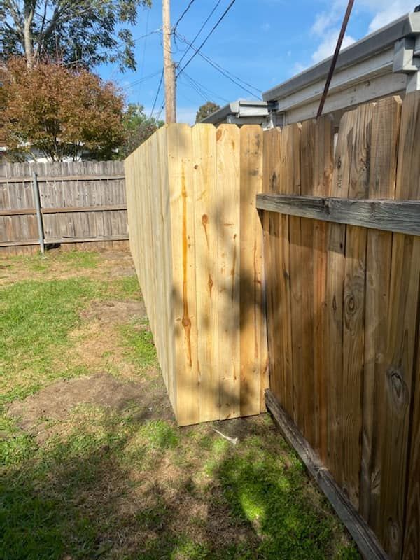 A wooden fence is sitting in the middle of a lush green yard.