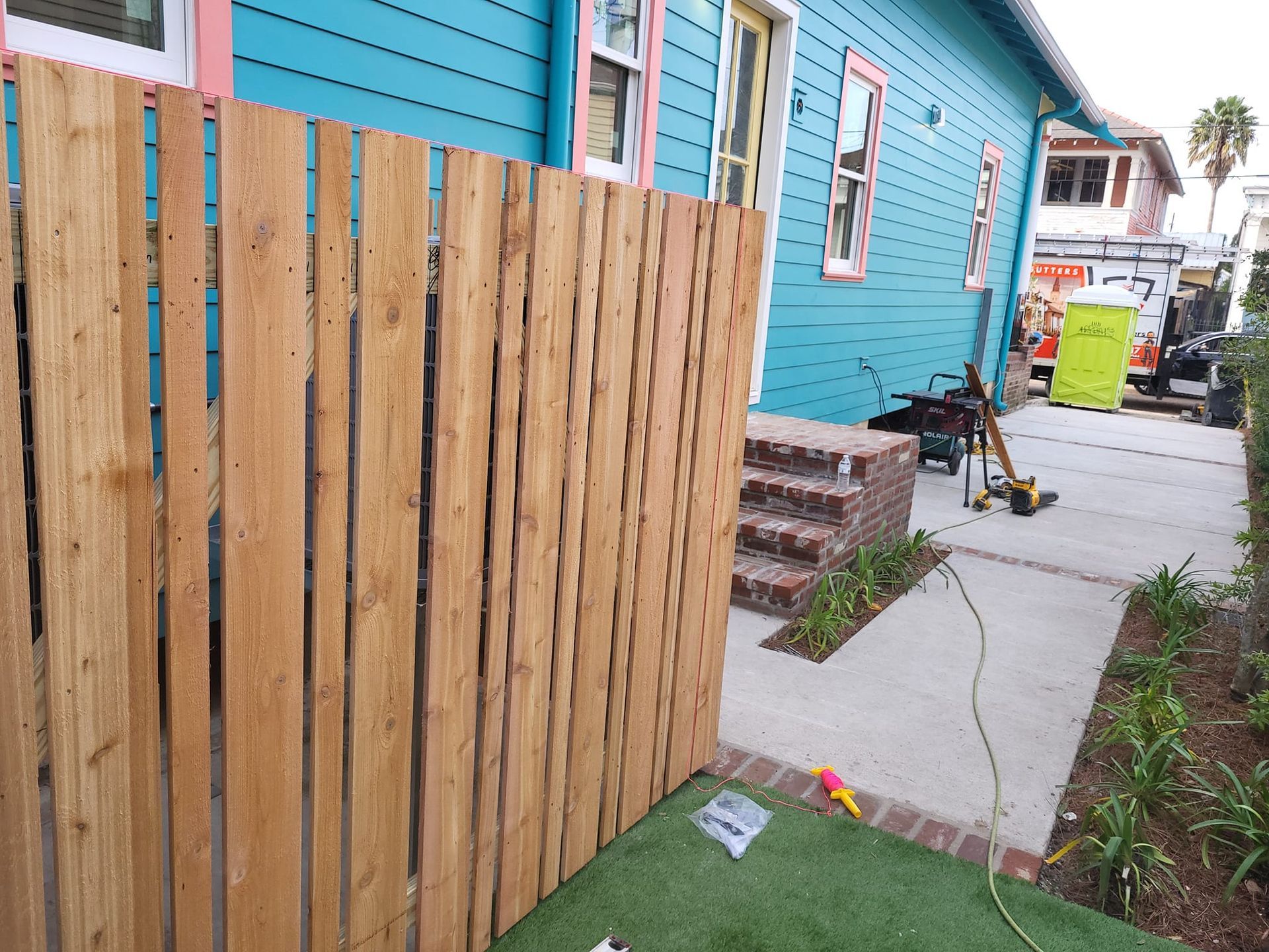 A wooden fence is being built in front of a blue house.