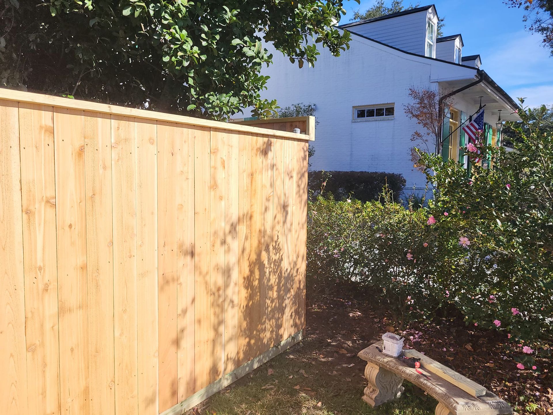 A wooden fence is in front of a white house.