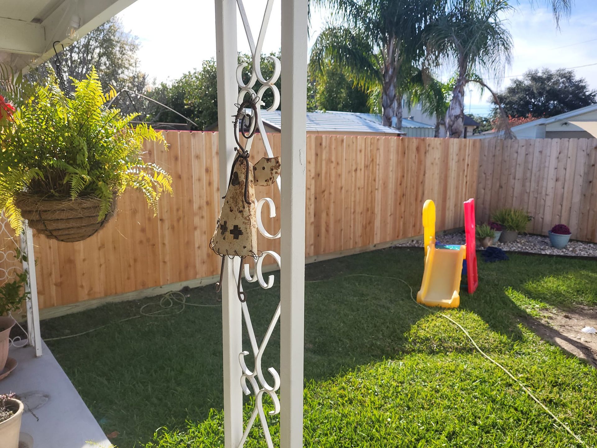 A backyard with a wooden fence and a slide.