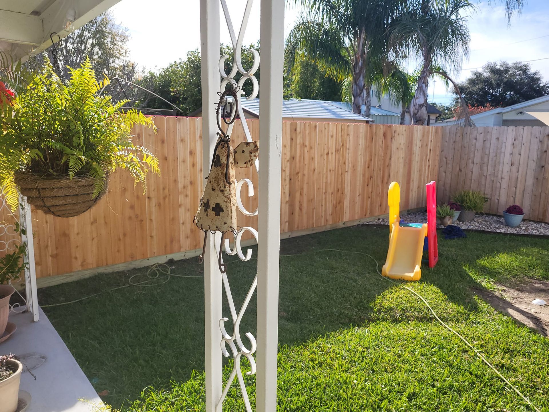 A backyard with a wooden fence and a slide.