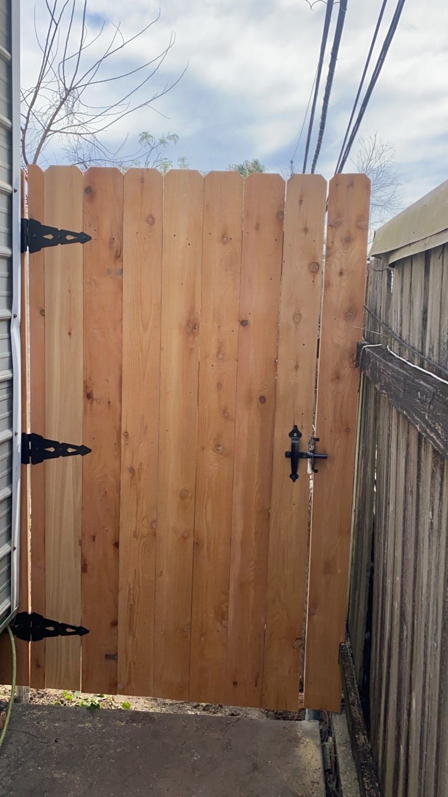 A wooden gate is sitting next to a wooden fence.