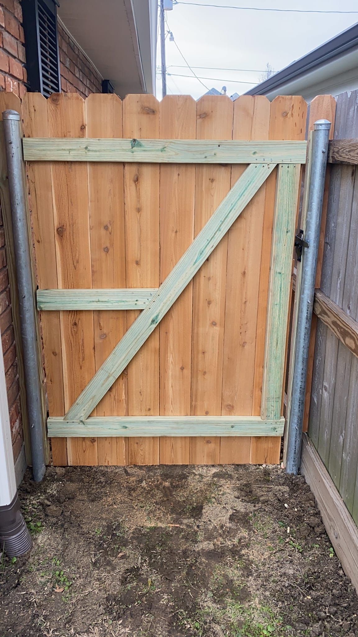 A wooden gate is attached to a wooden fence.