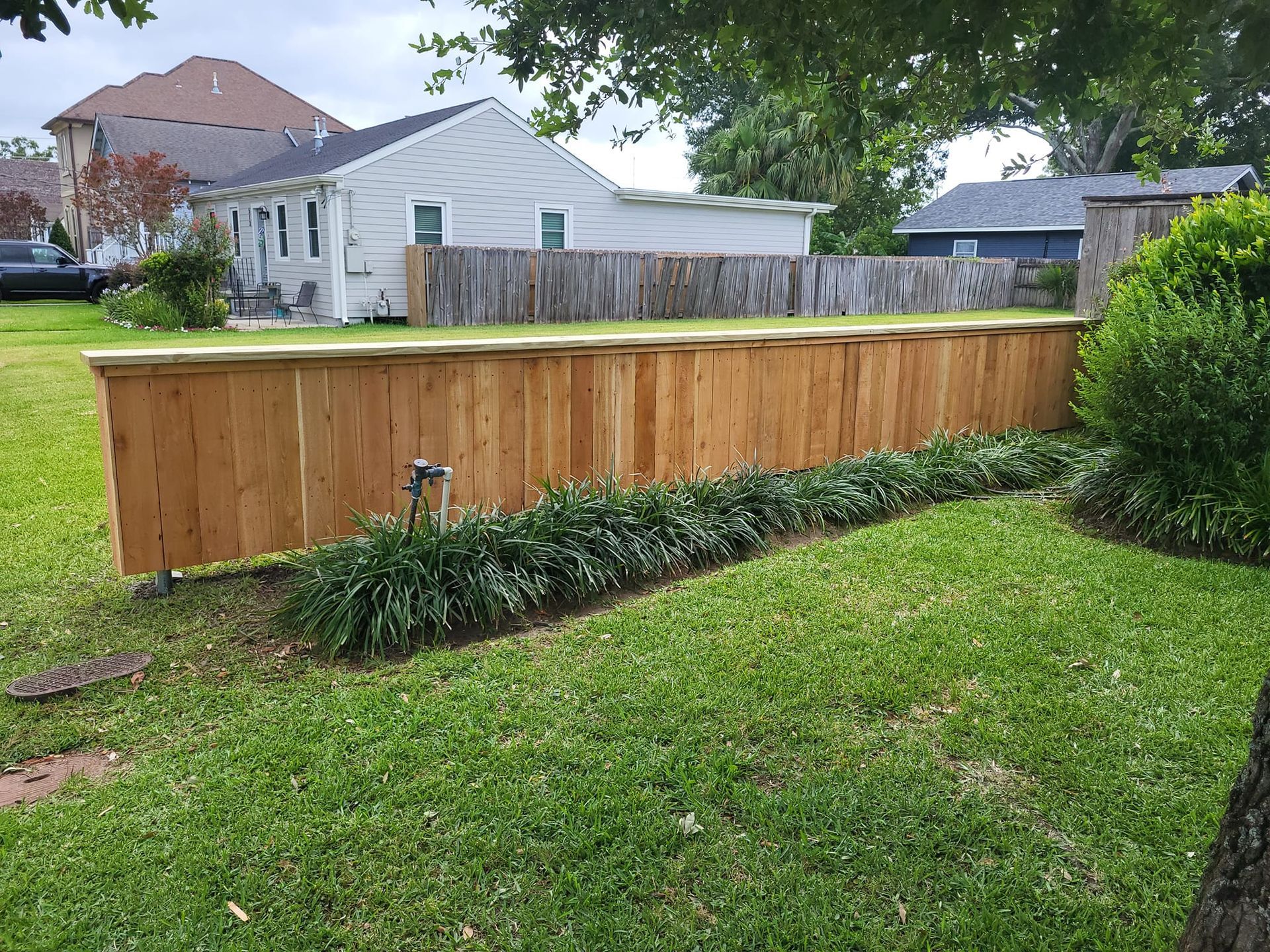 A wooden fence is in the middle of a lush green yard.