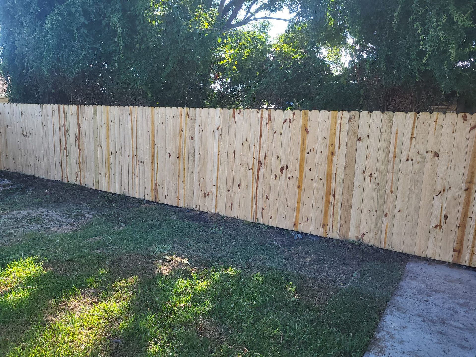 A wooden fence is in the backyard of a house.