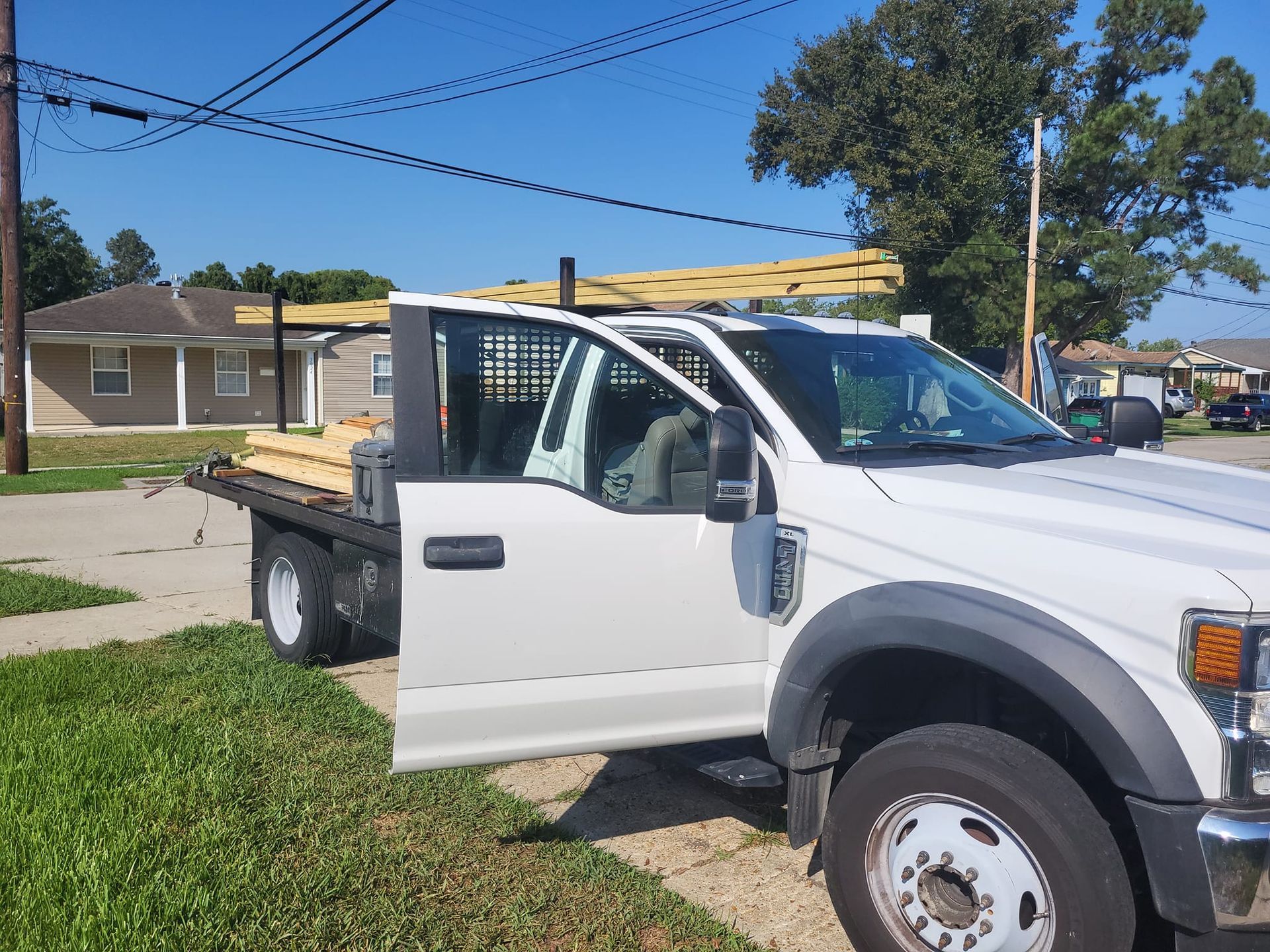 A white truck with a flatbed is parked on the side of the road.