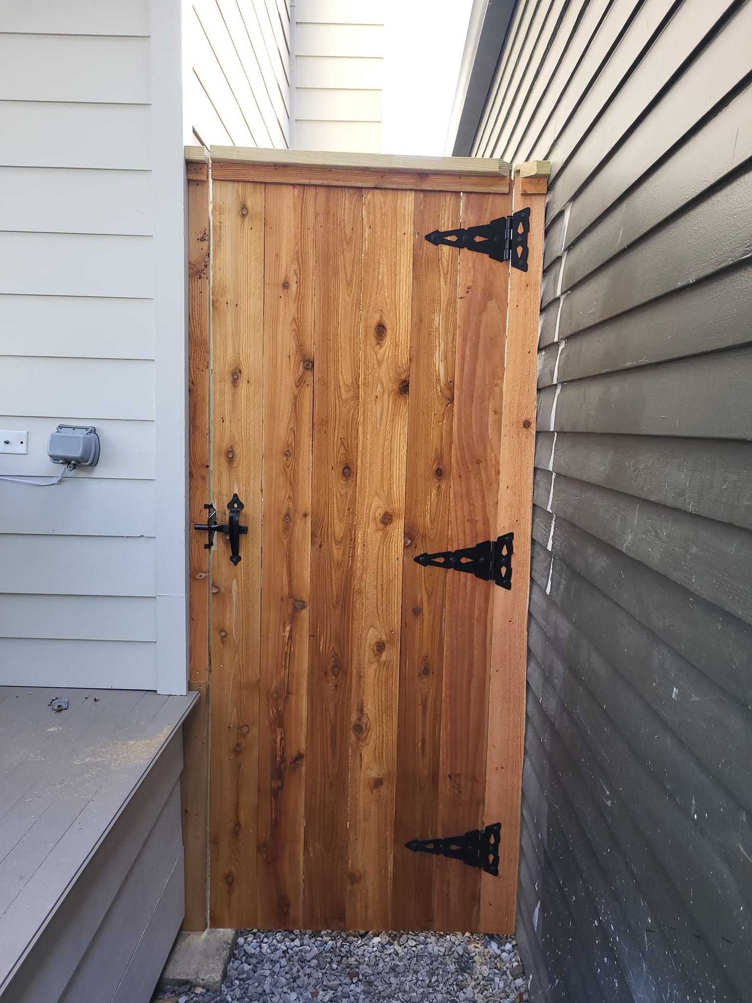 A wooden door with black hinges is between two houses