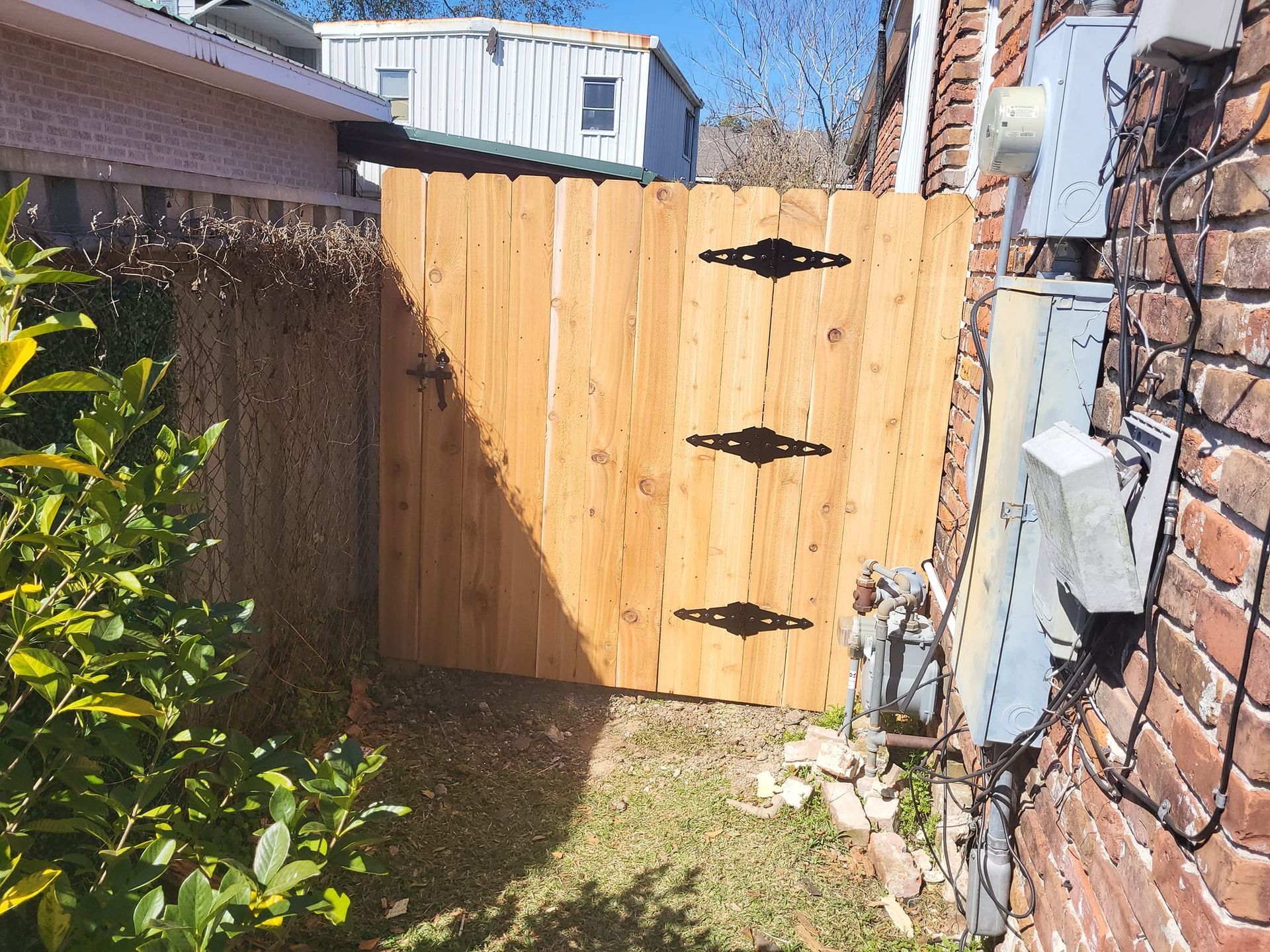 A wooden gate is sitting next to a brick wall.