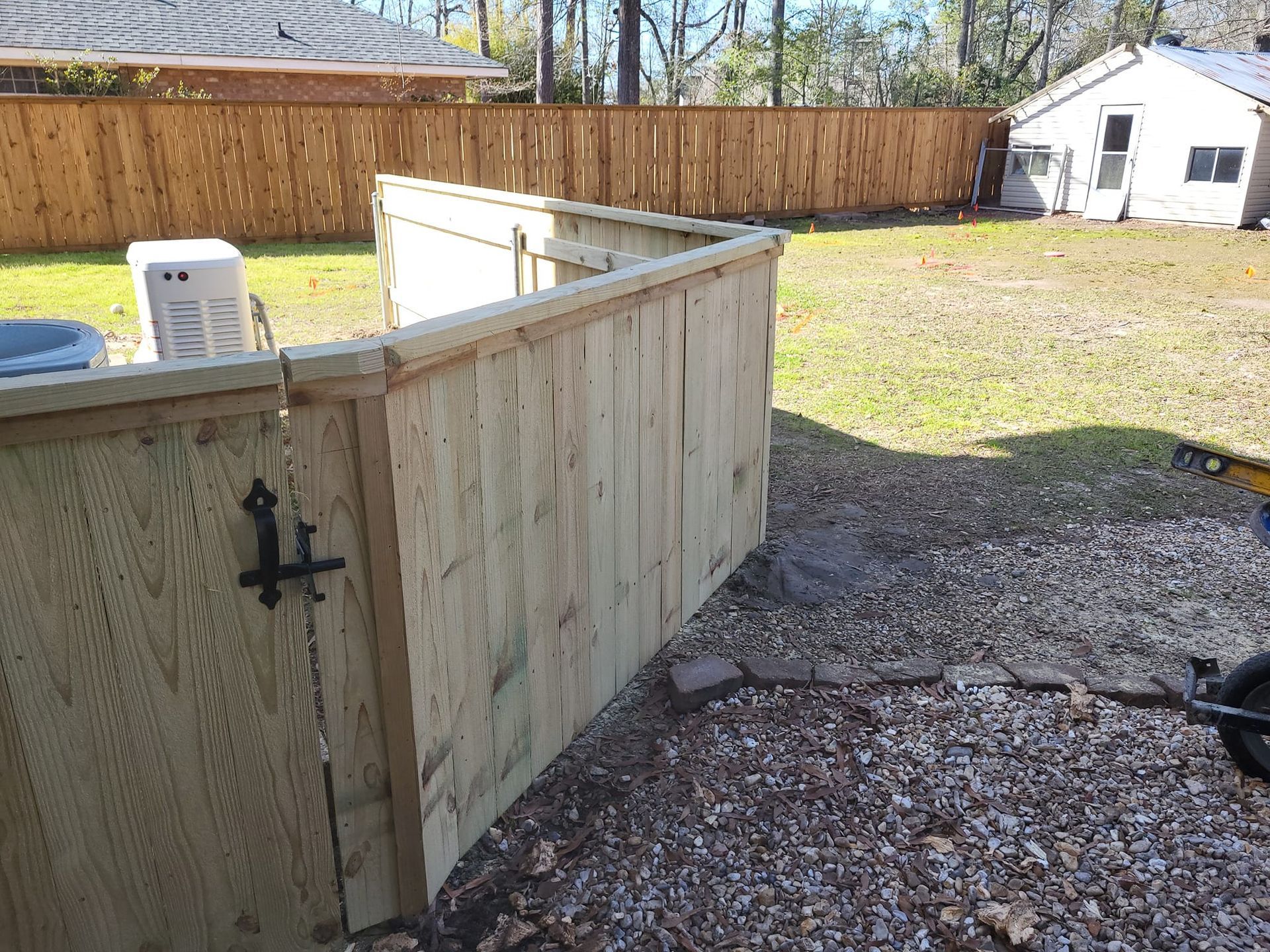 A wooden fence is being built in the backyard of a house.