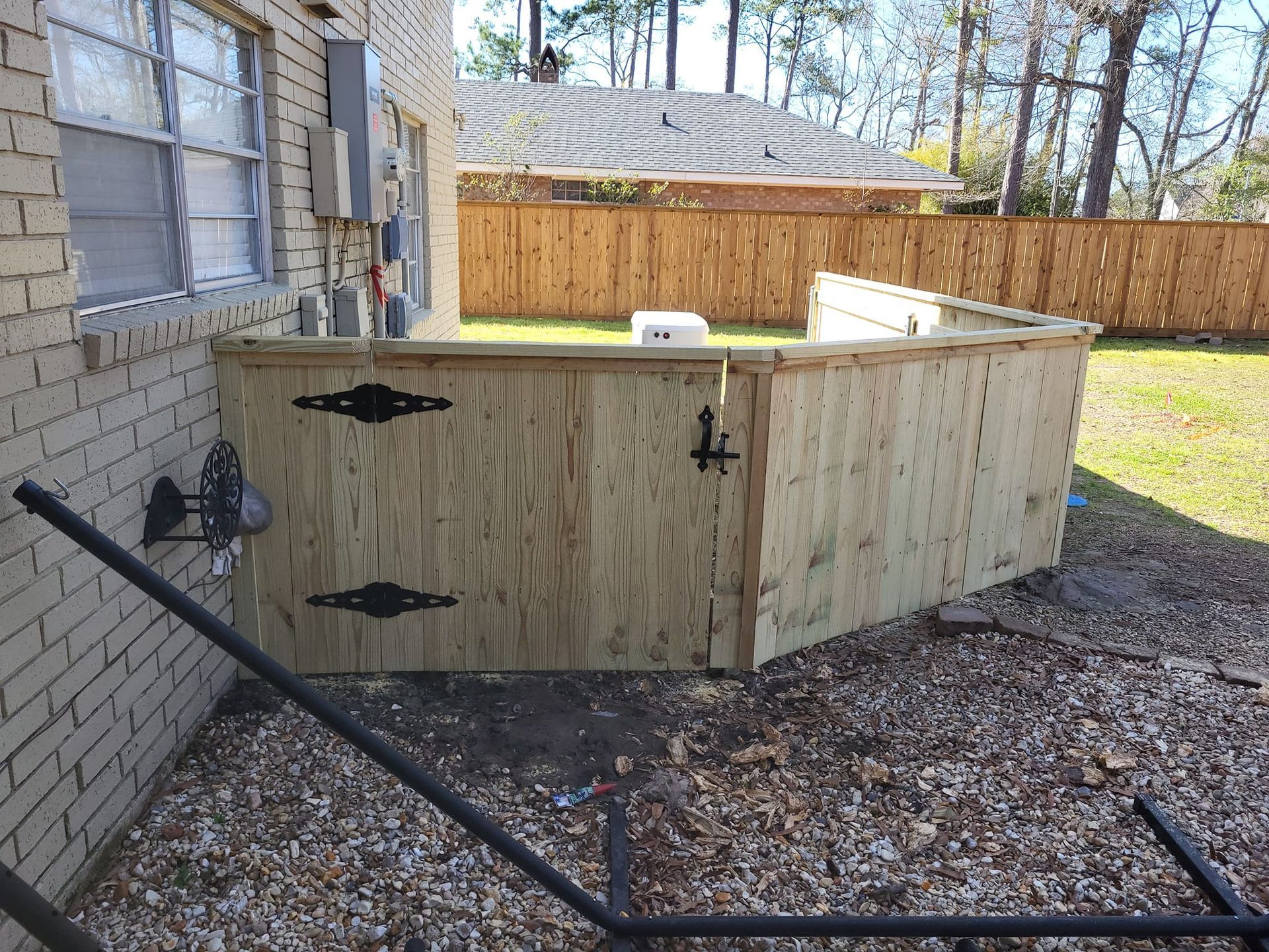 A wooden fence is sitting in front of a brick house.