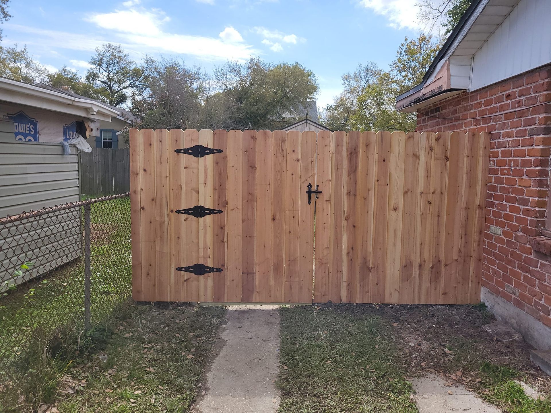 A wooden fence with a gate is in front of a brick house.