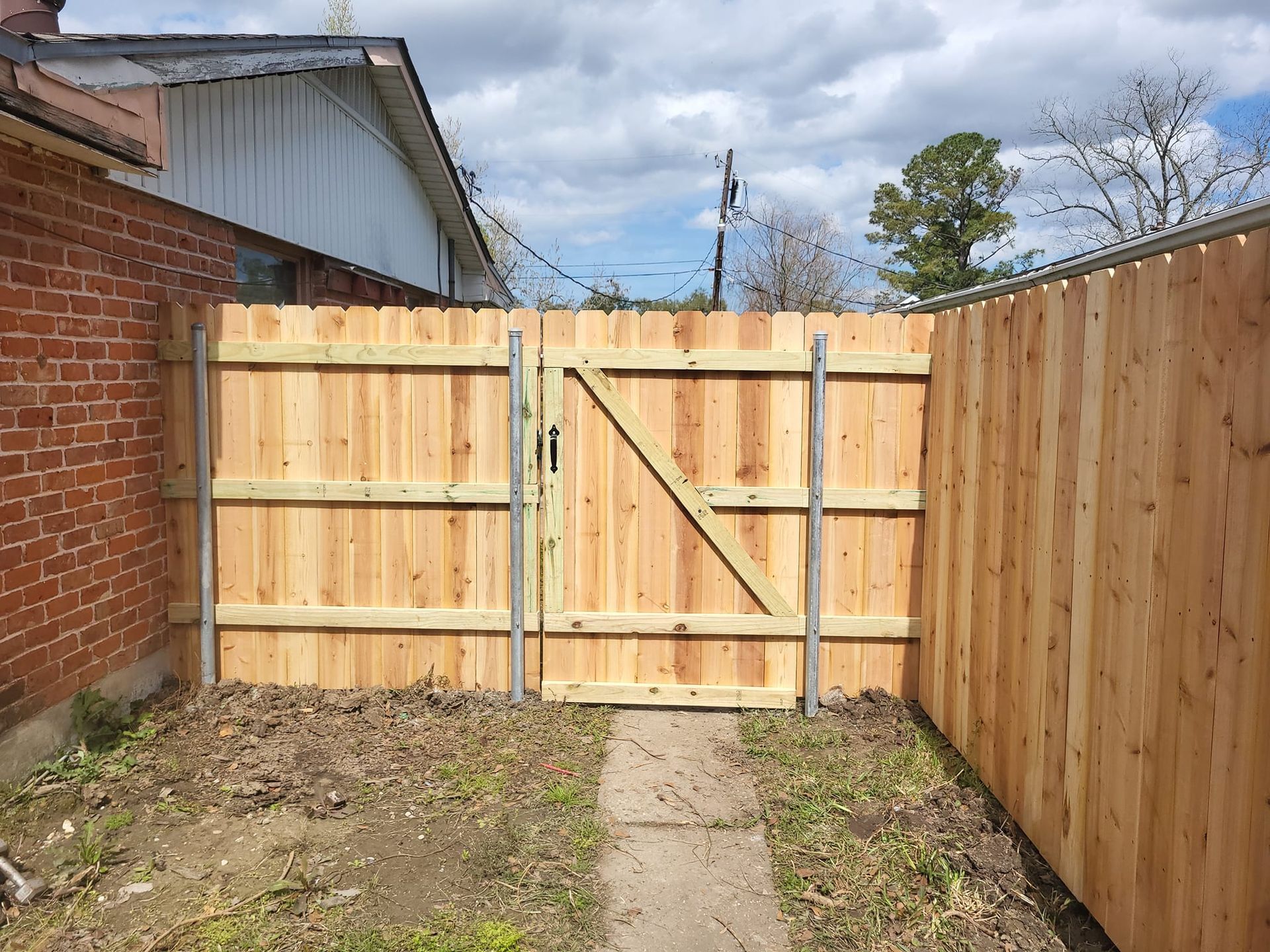 A wooden fence with a gate in the backyard of a house.