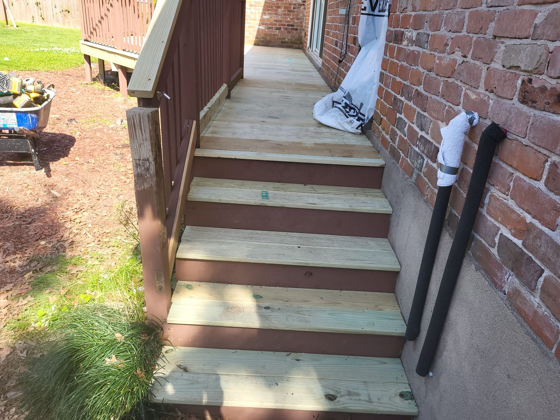 A wooden deck with stairs leading up to a brick building.