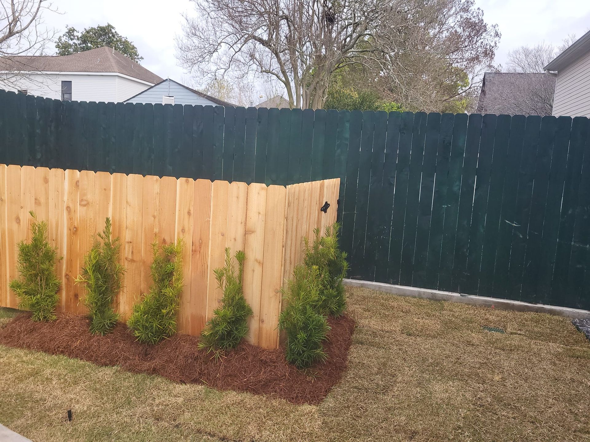 A wooden fence with a green fence behind it