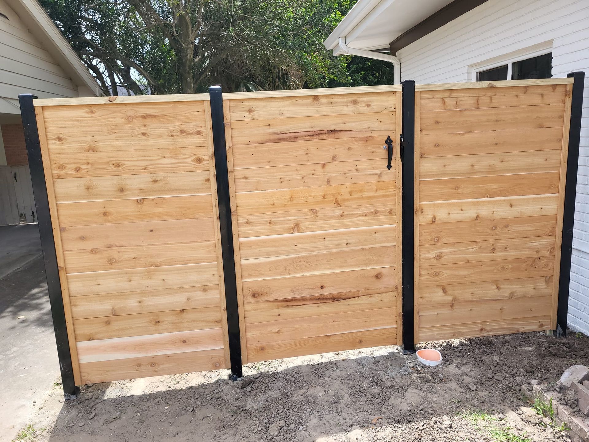 A wooden fence with a gate in front of a white house.