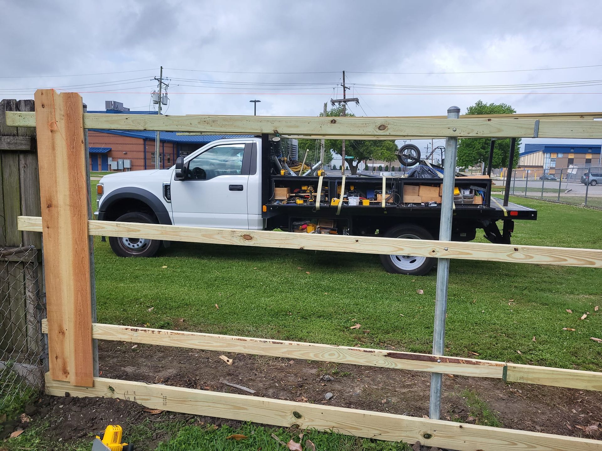 A white truck is parked next to a wooden fence.