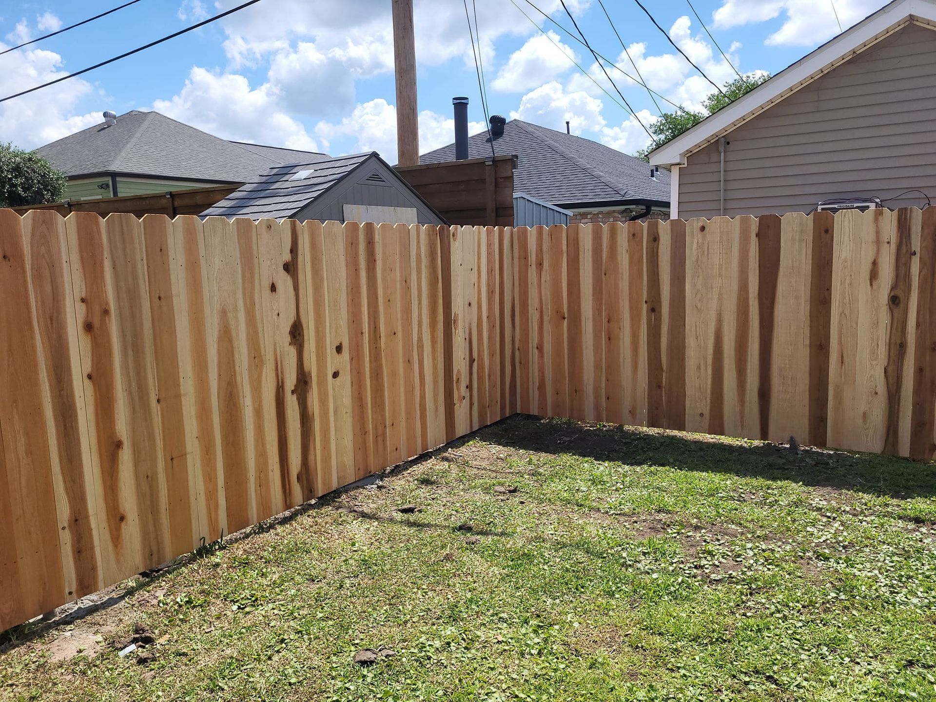 A wooden fence is in the backyard of a house.