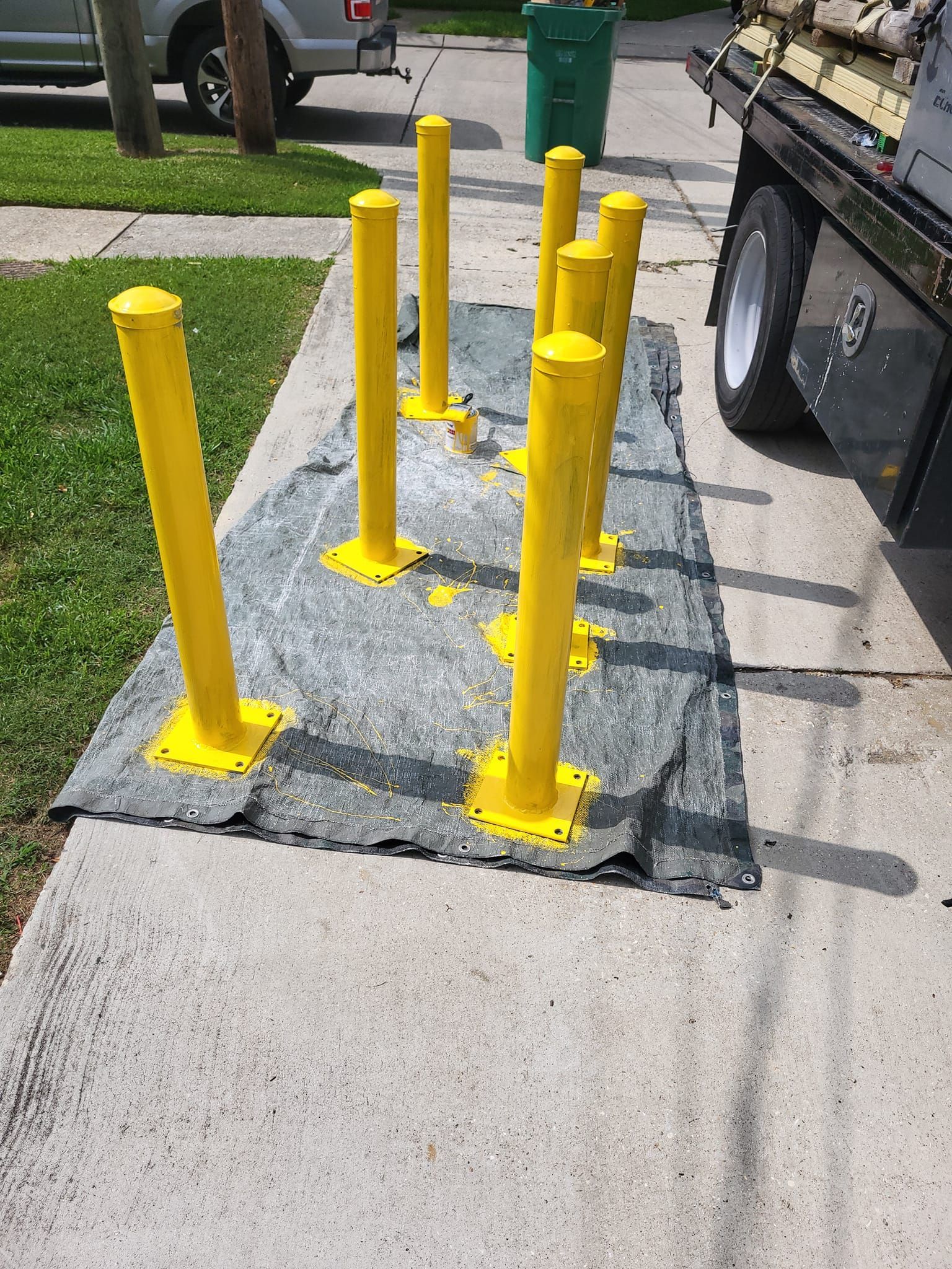 A bunch of yellow poles are sitting on a sidewalk