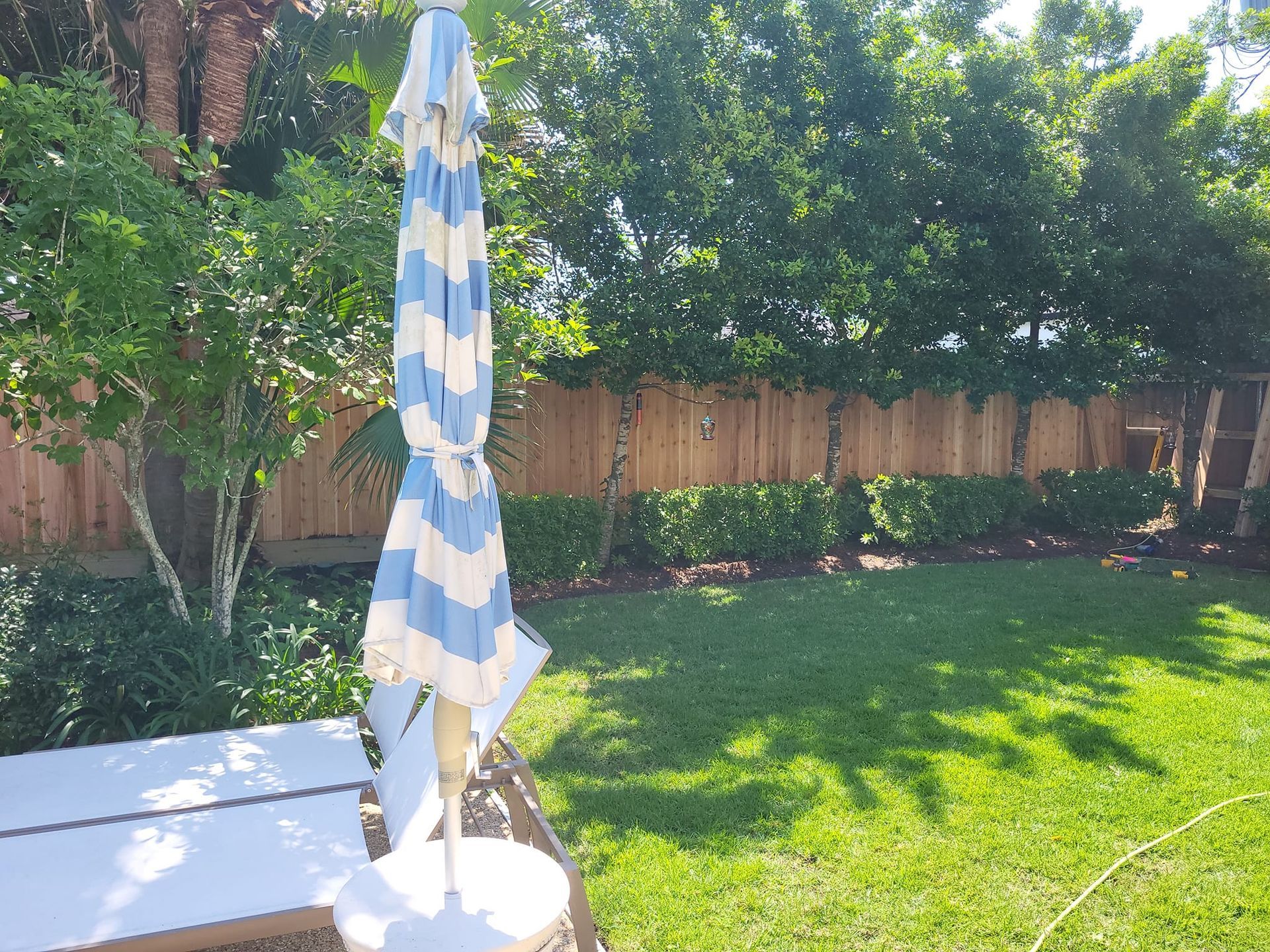 There is a blue and white striped umbrella in the backyard.