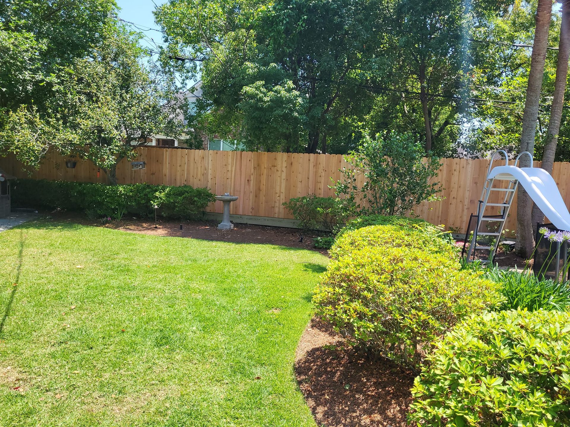 A backyard with a wooden fence and a slide.