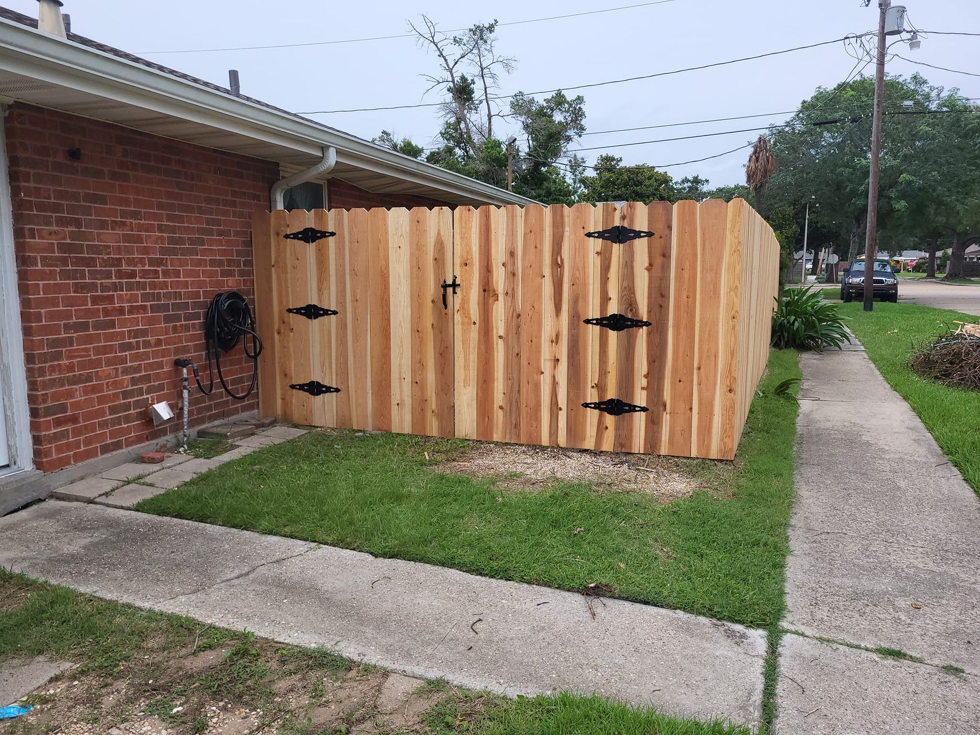A wooden fence is sitting in front of a brick house.