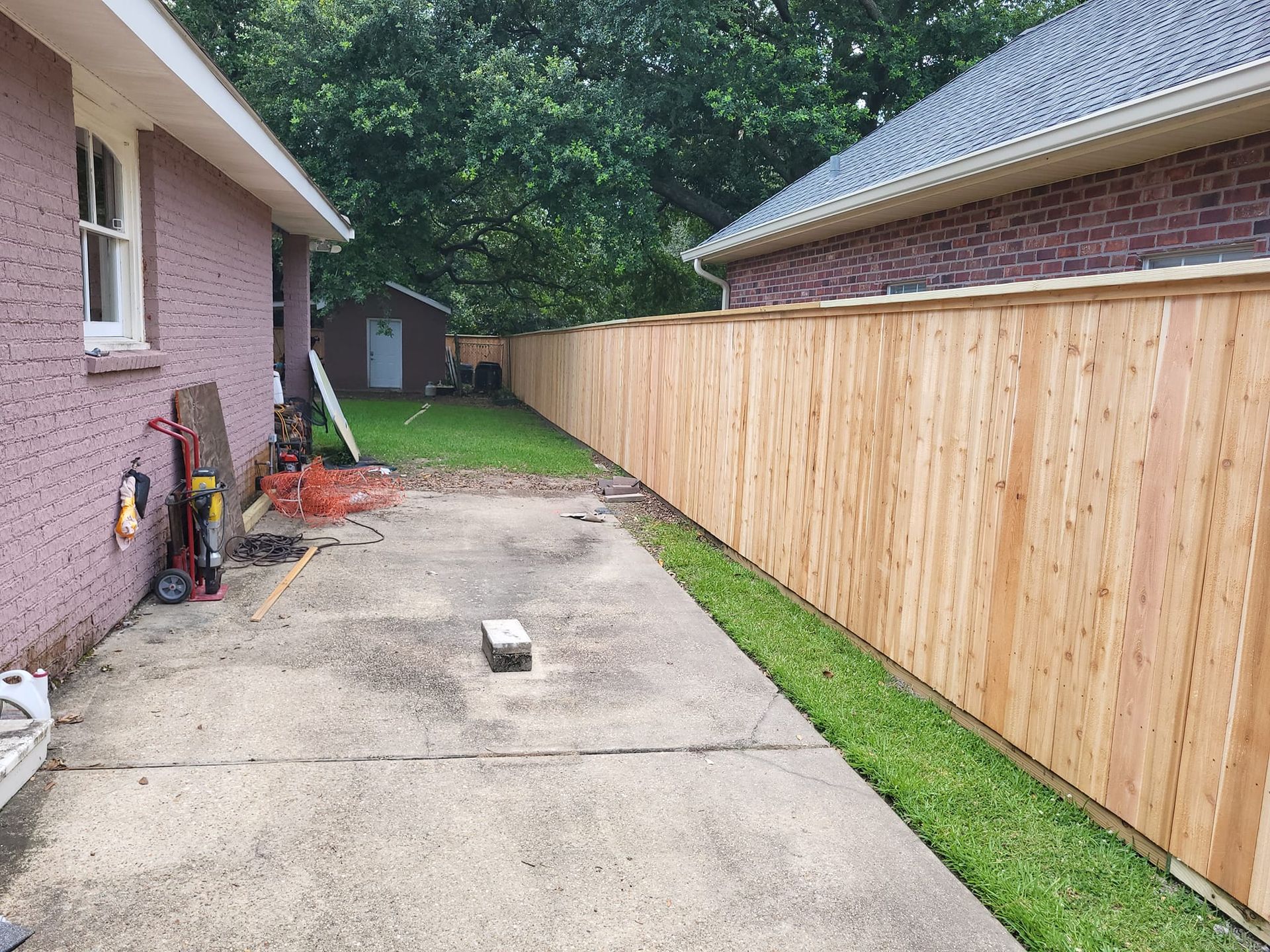 A wooden fence is being built in front of a brick house.