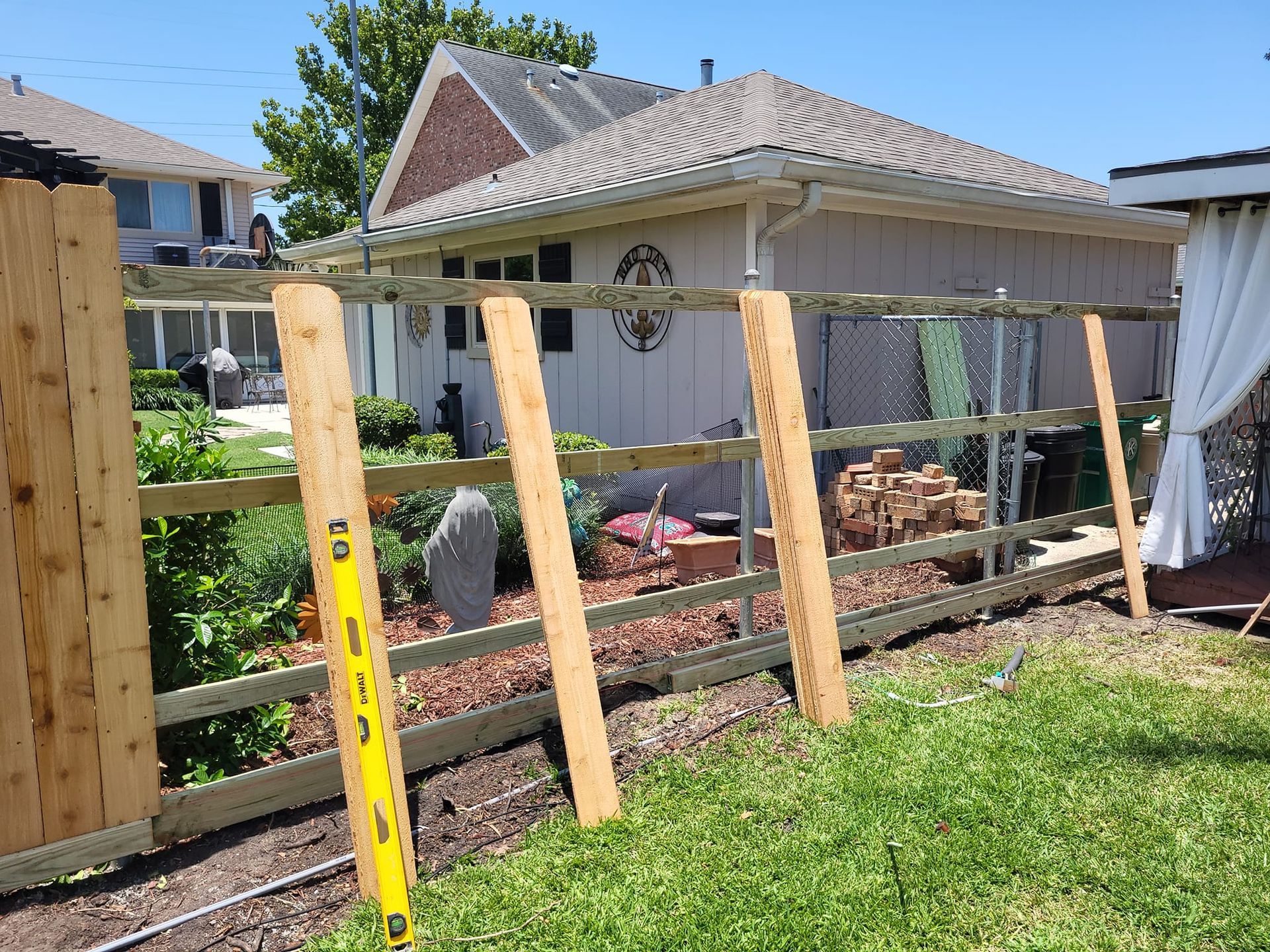 A wooden fence is being built in the backyard of a house.