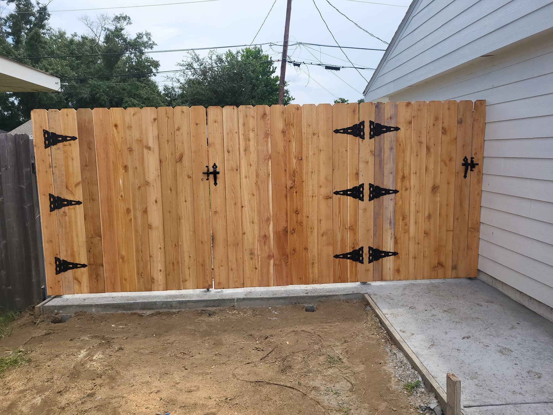 A wooden fence with black hinges is in front of a house.