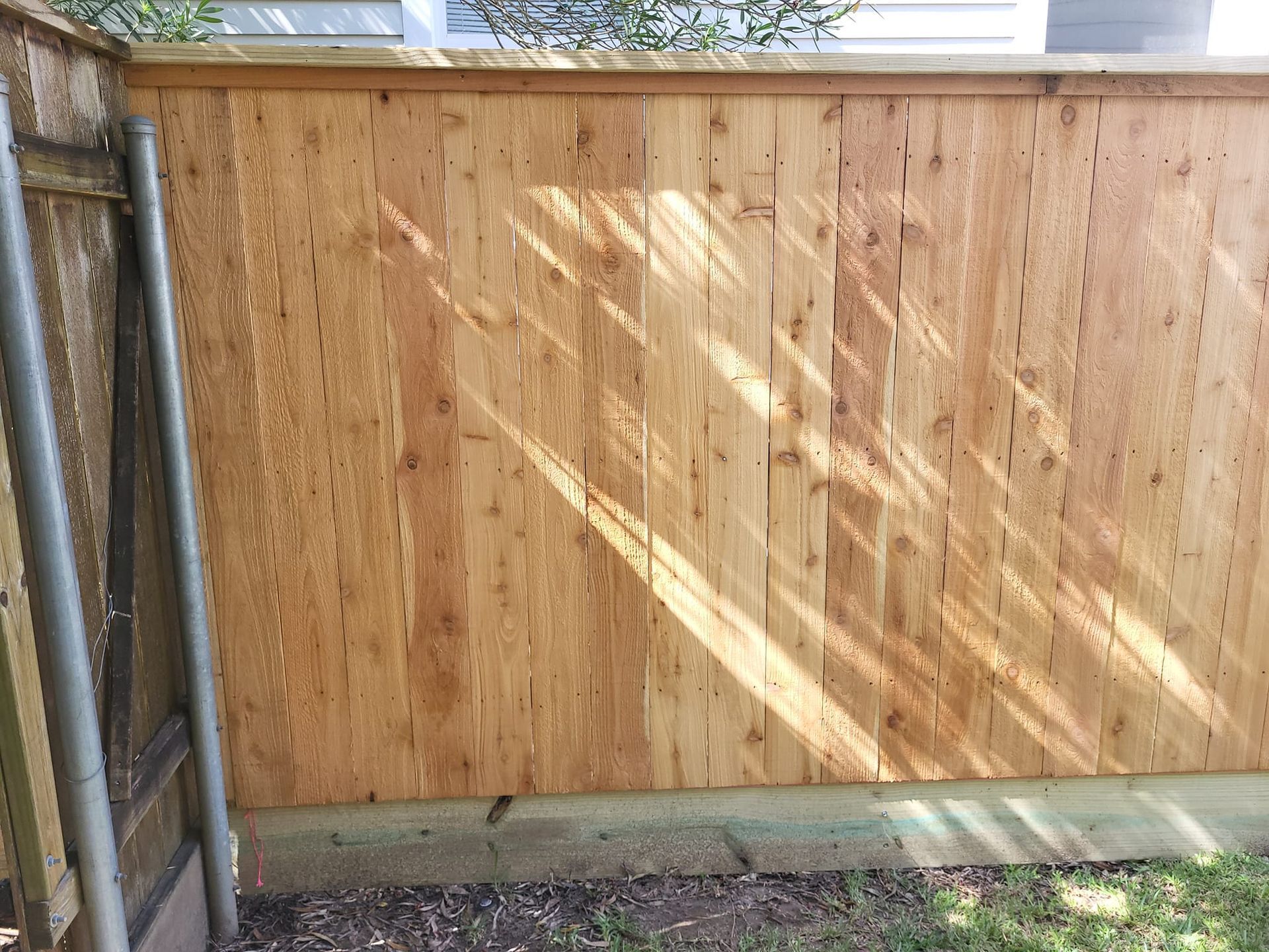 A wooden fence is sitting in the backyard of a house.