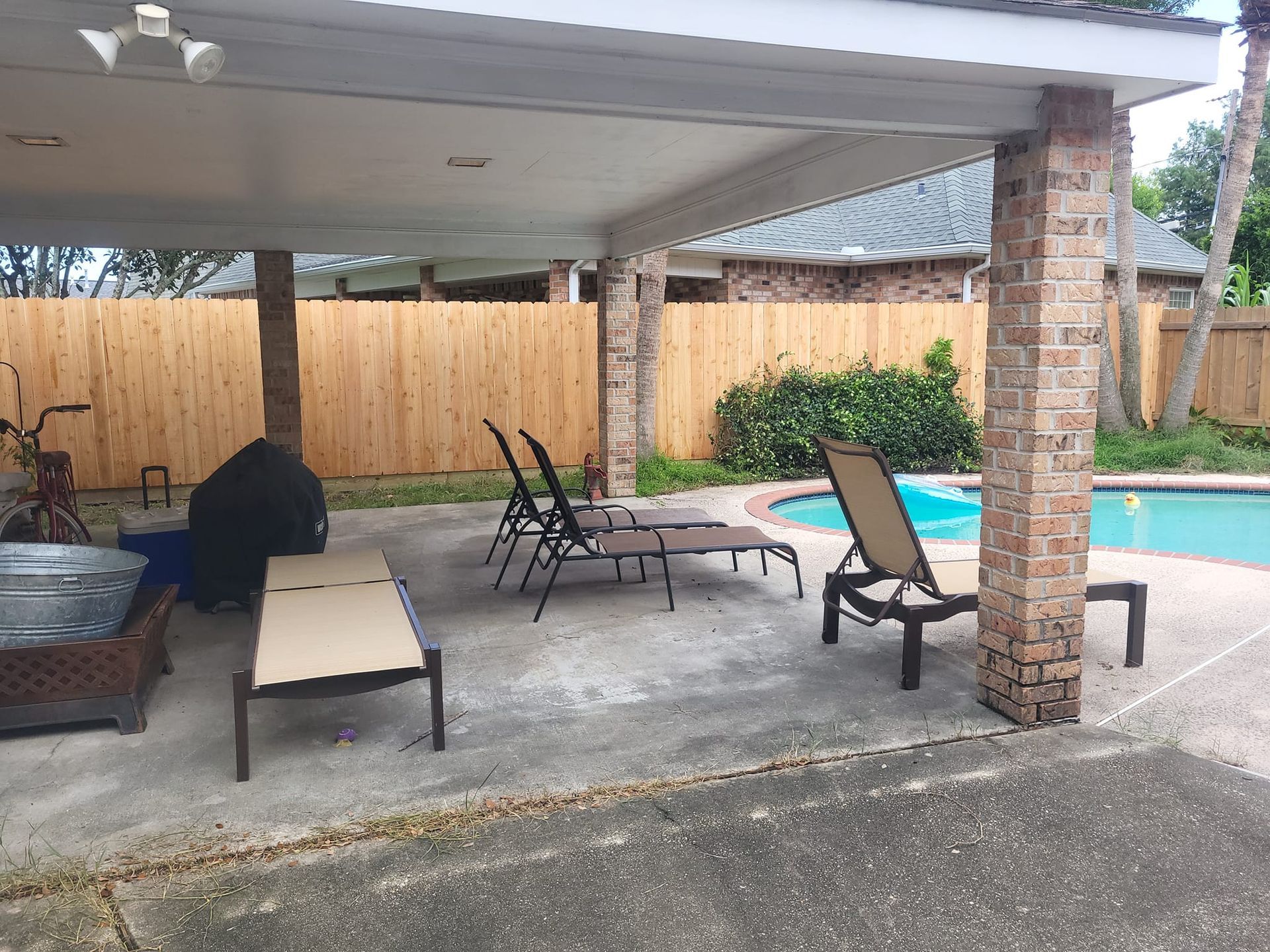 A patio with chairs and a fire pit next to a swimming pool