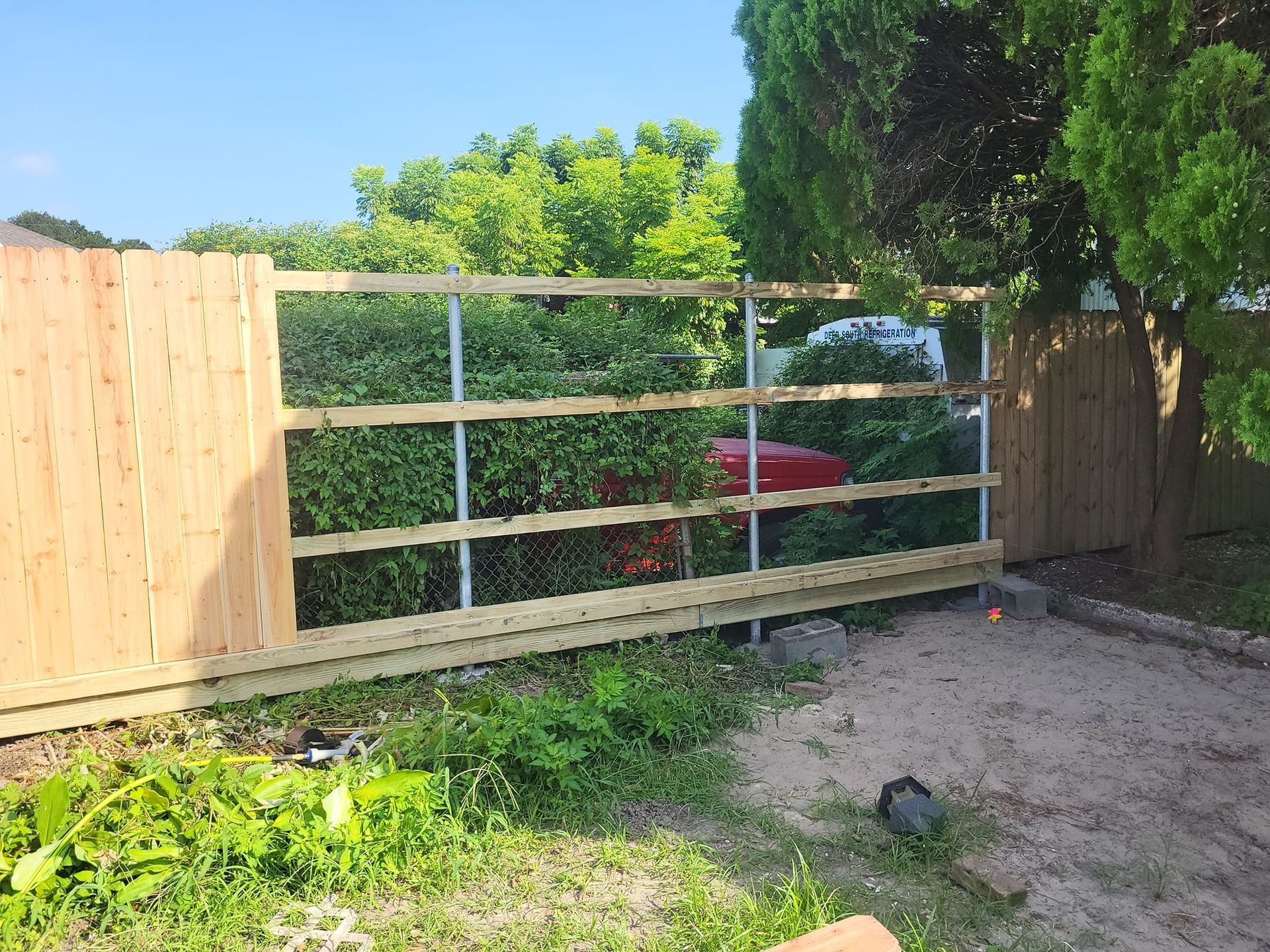 A wooden fence is being built in the backyard of a house.