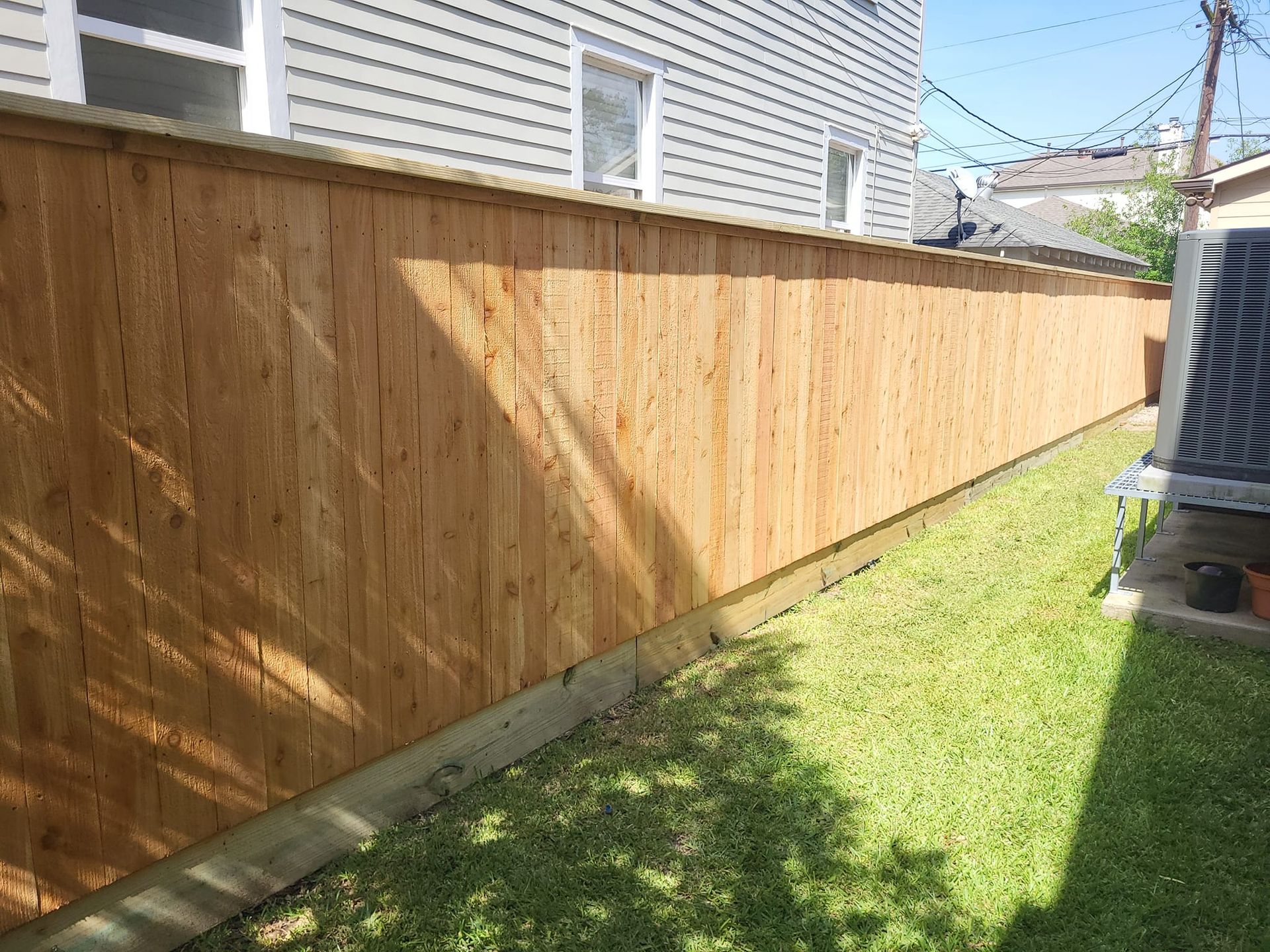 A wooden fence is in the backyard of a house.