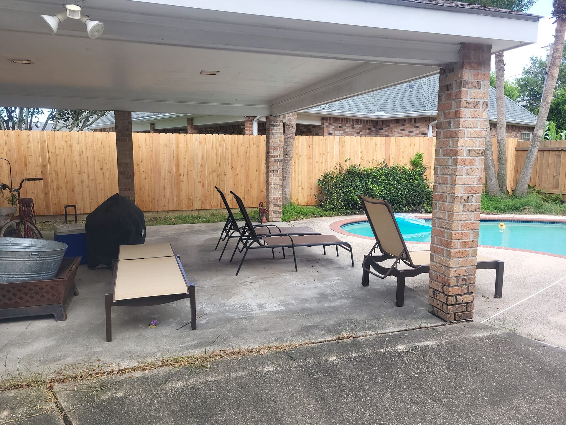 A patio area with chairs and a bicycle in front of a swimming pool.