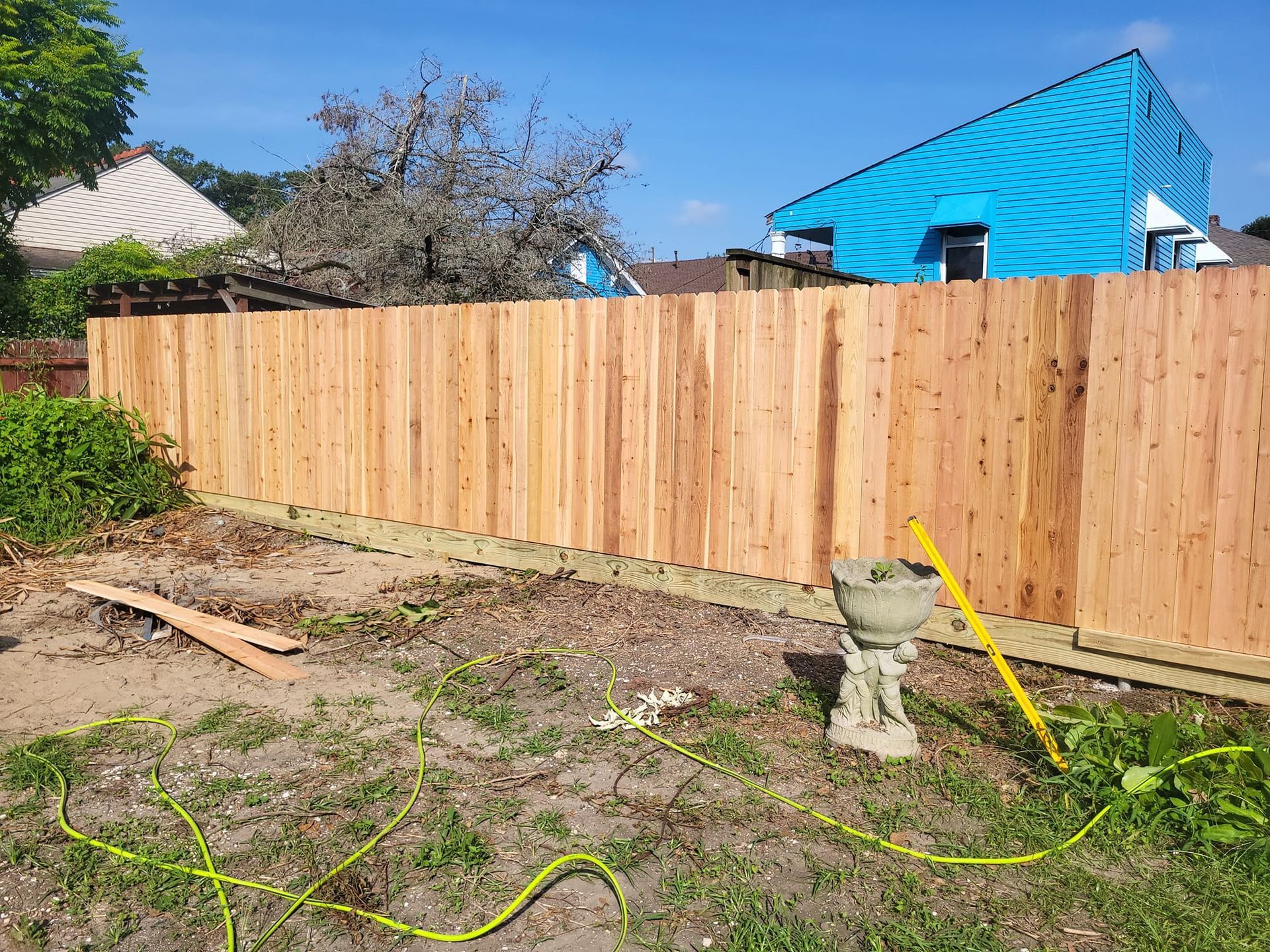 A wooden fence is being built in the backyard of a house.