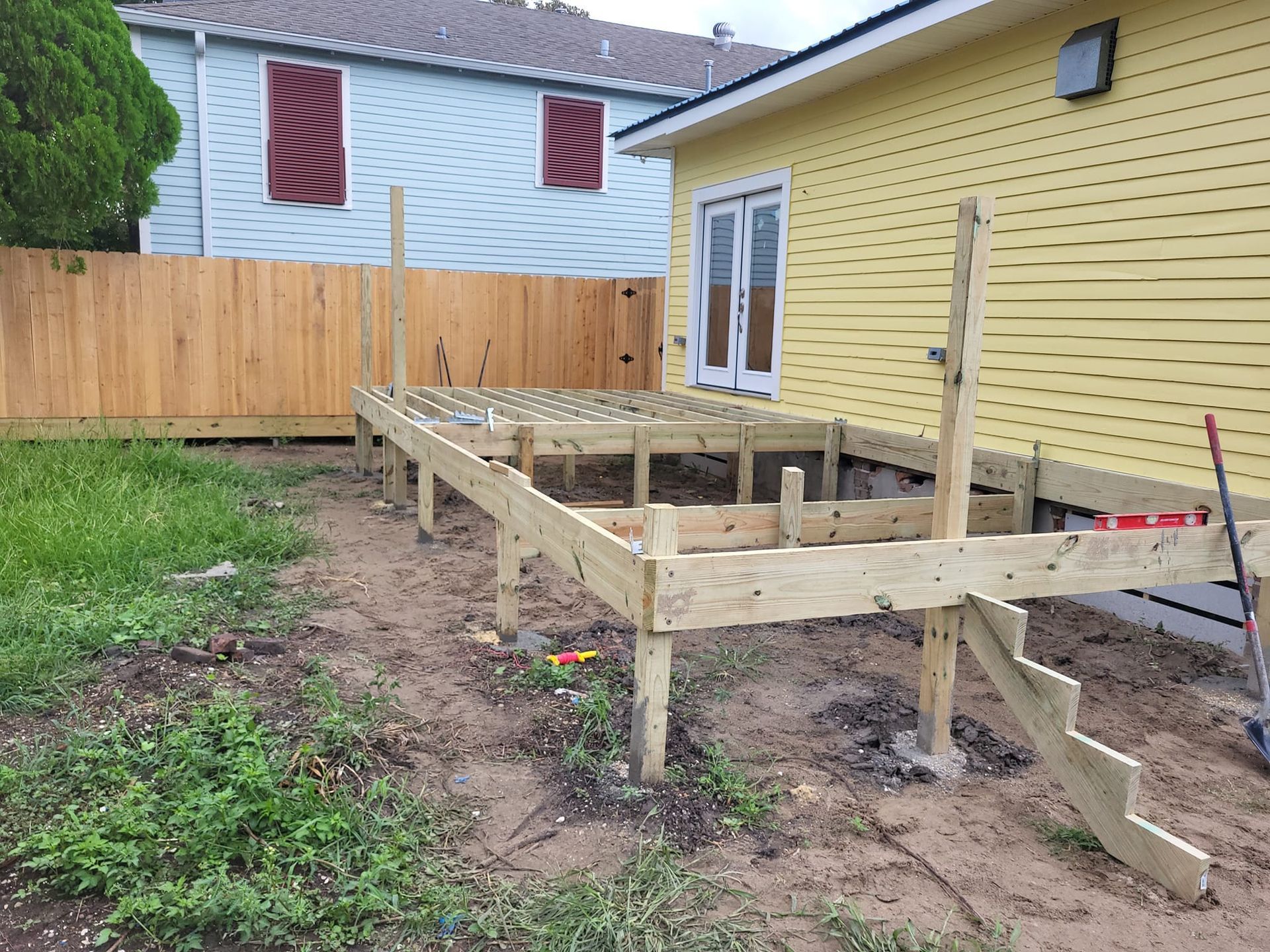 A wooden deck is being built in the backyard of a house.