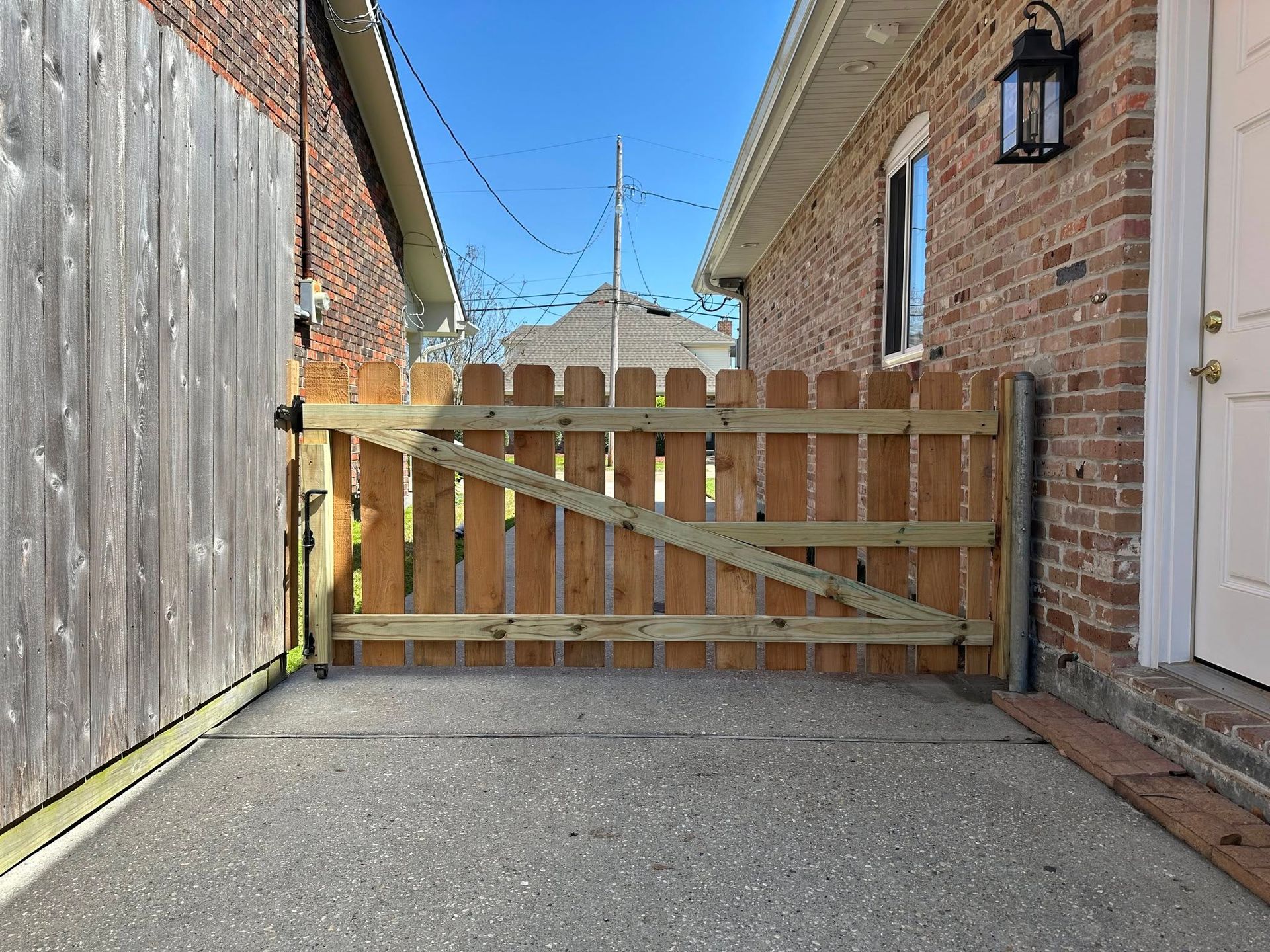 A wooden fence is between two brick houses.