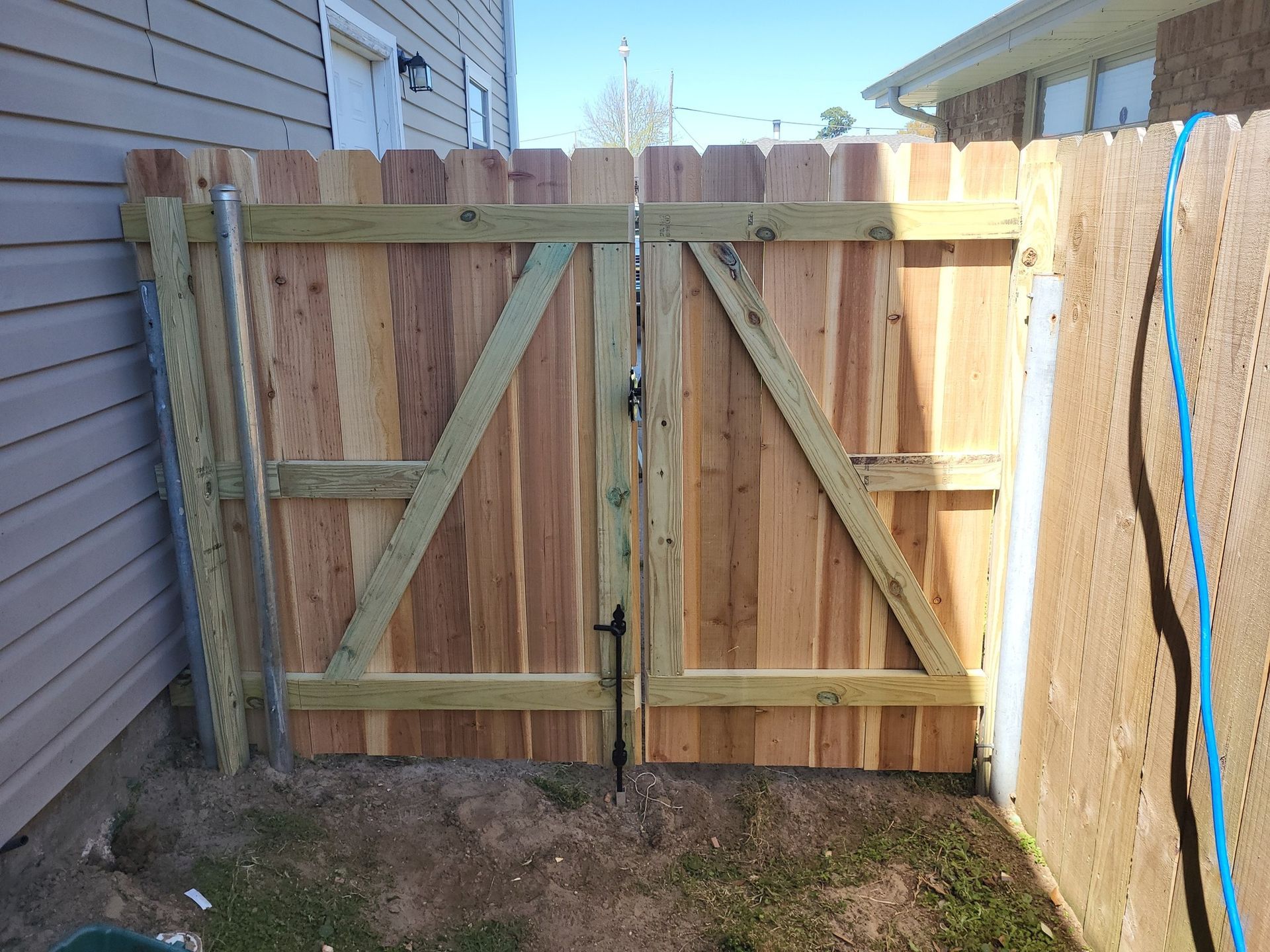 A wooden fence with a gate in the backyard of a house