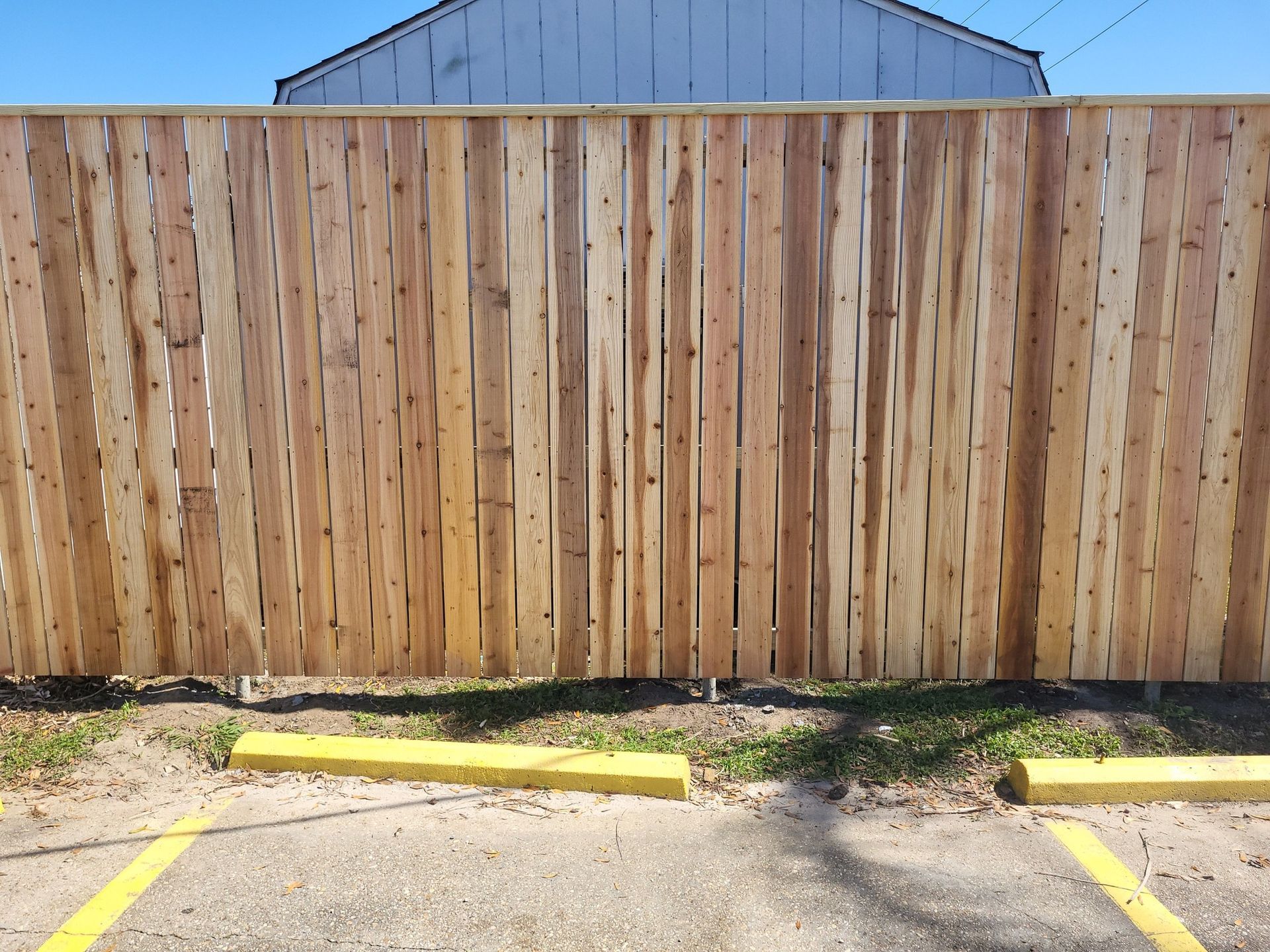 A wooden fence is surrounding a parking lot.