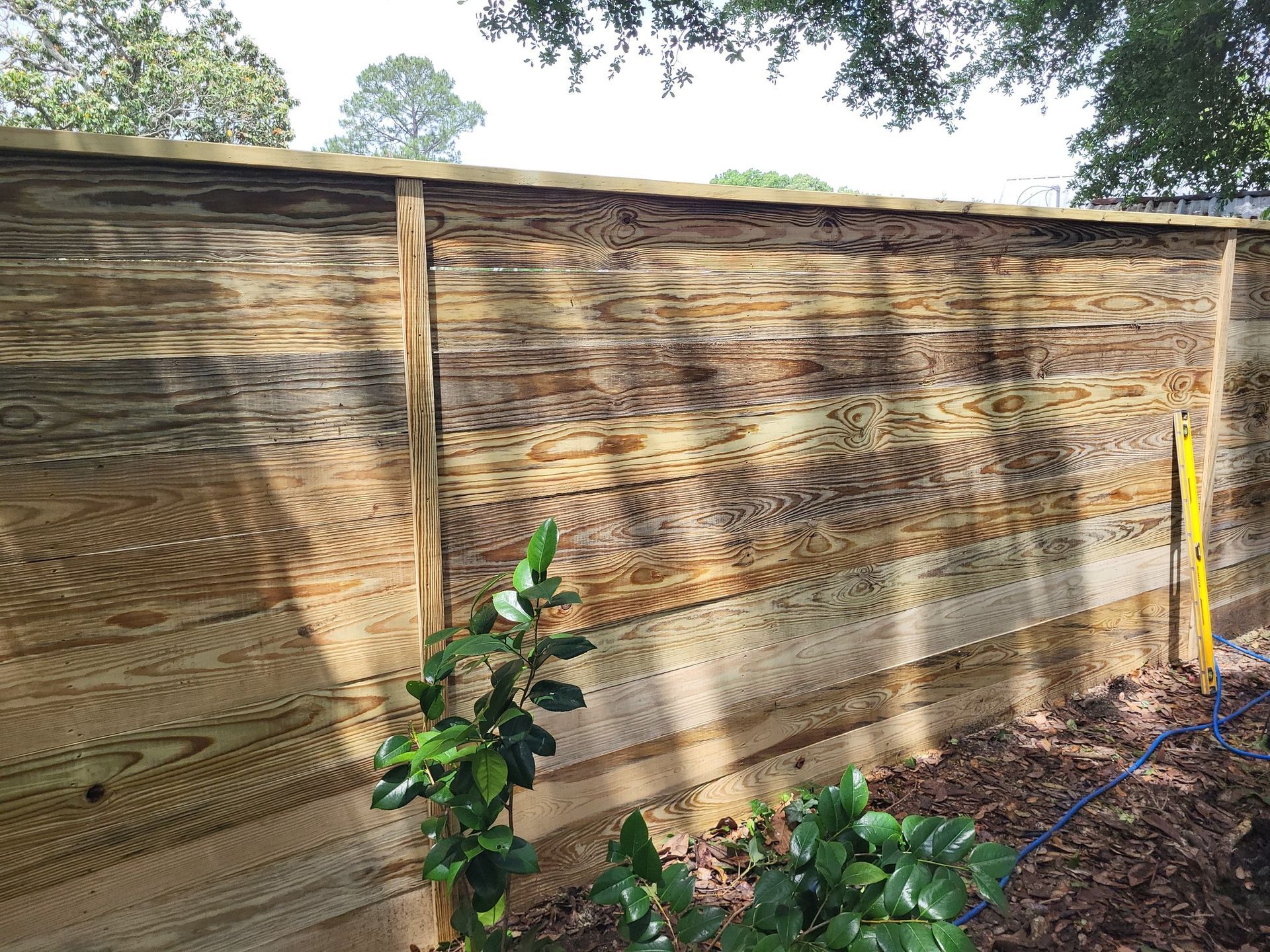 A wooden fence is surrounded by trees and a yellow level.