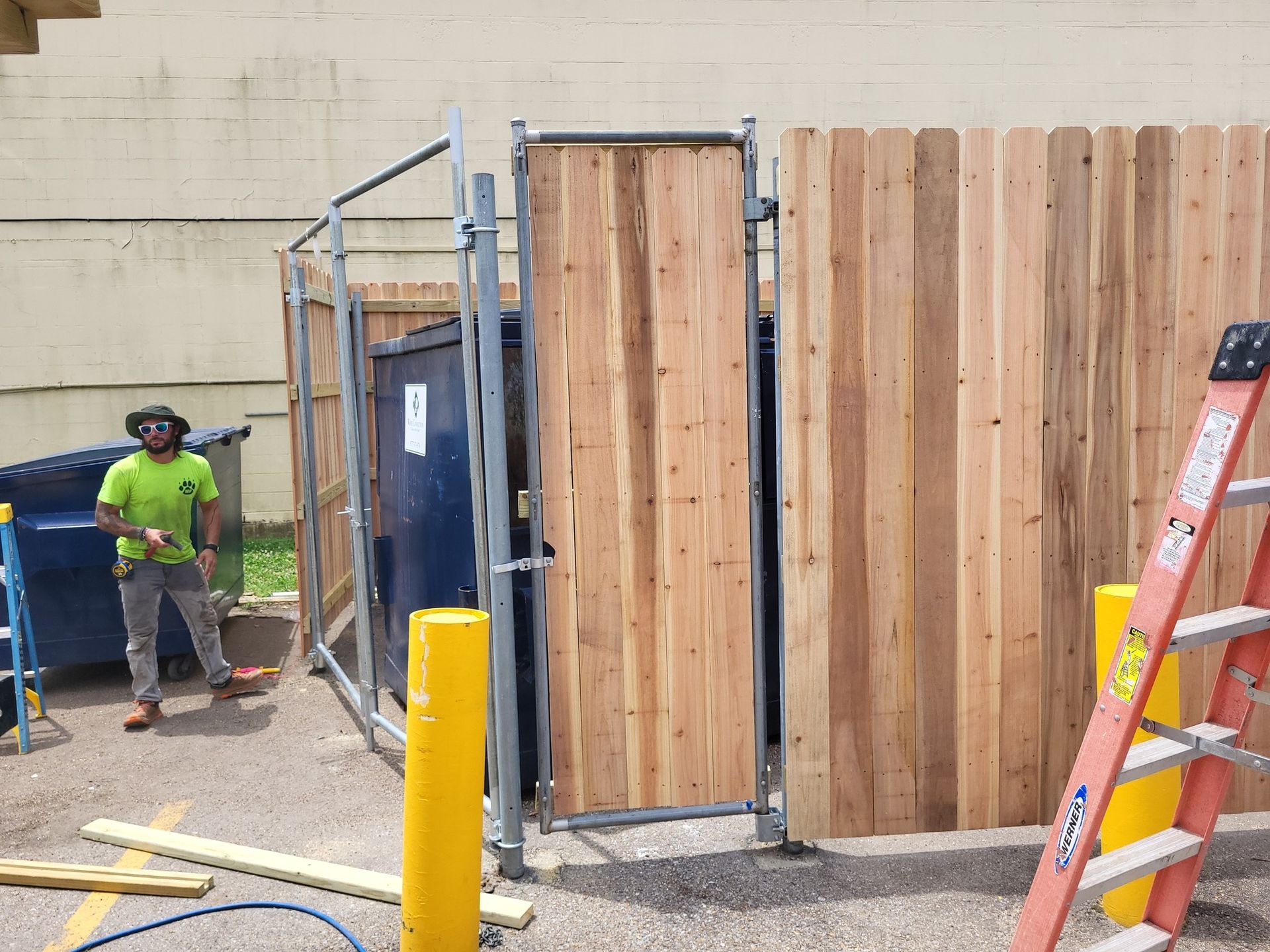 A man is standing in front of a wooden fence.