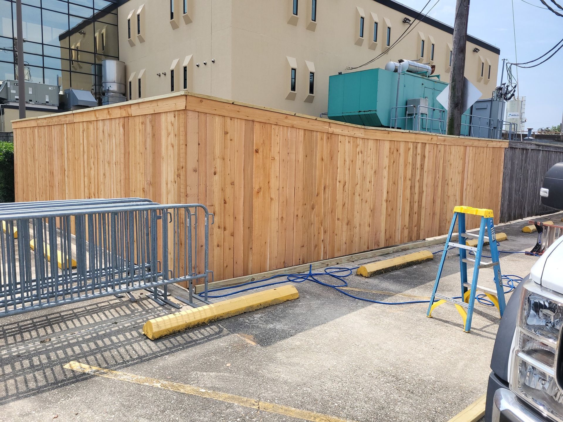 A wooden fence is being built in a parking lot in front of a building.