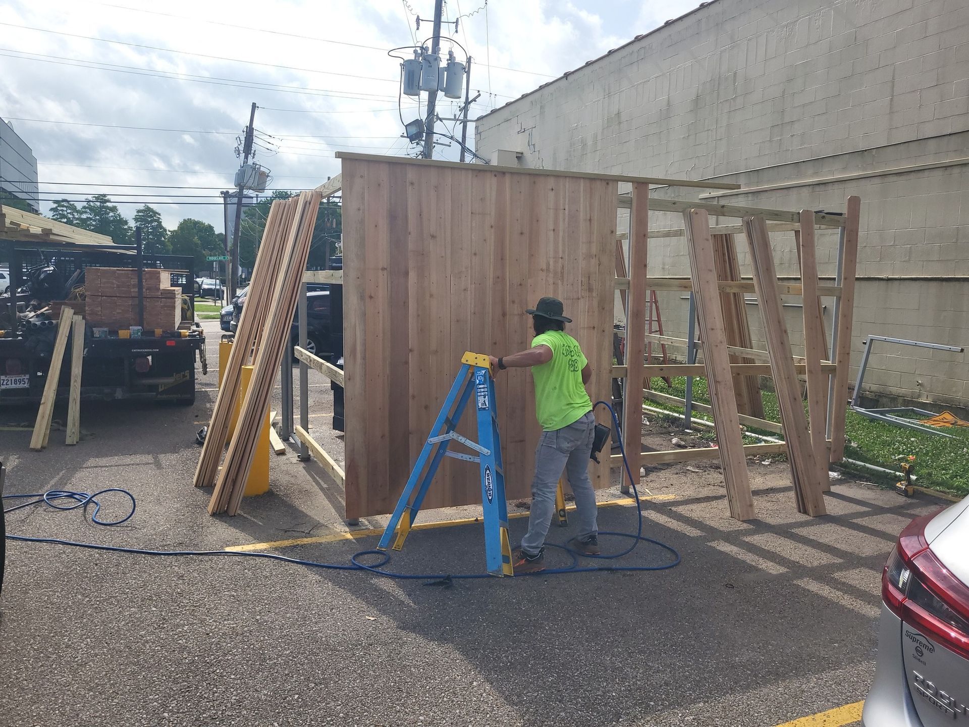 A man is standing on a ladder next to a wooden wall.