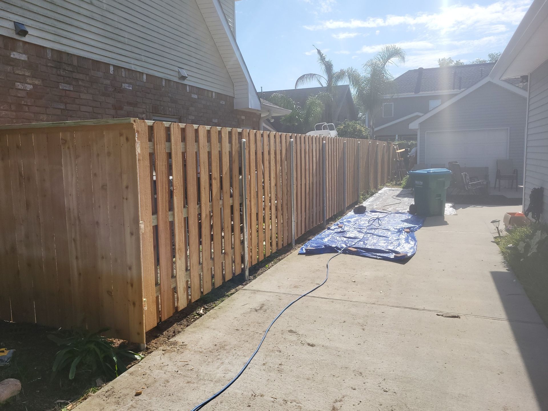 A wooden fence is being built in the backyard of a house.