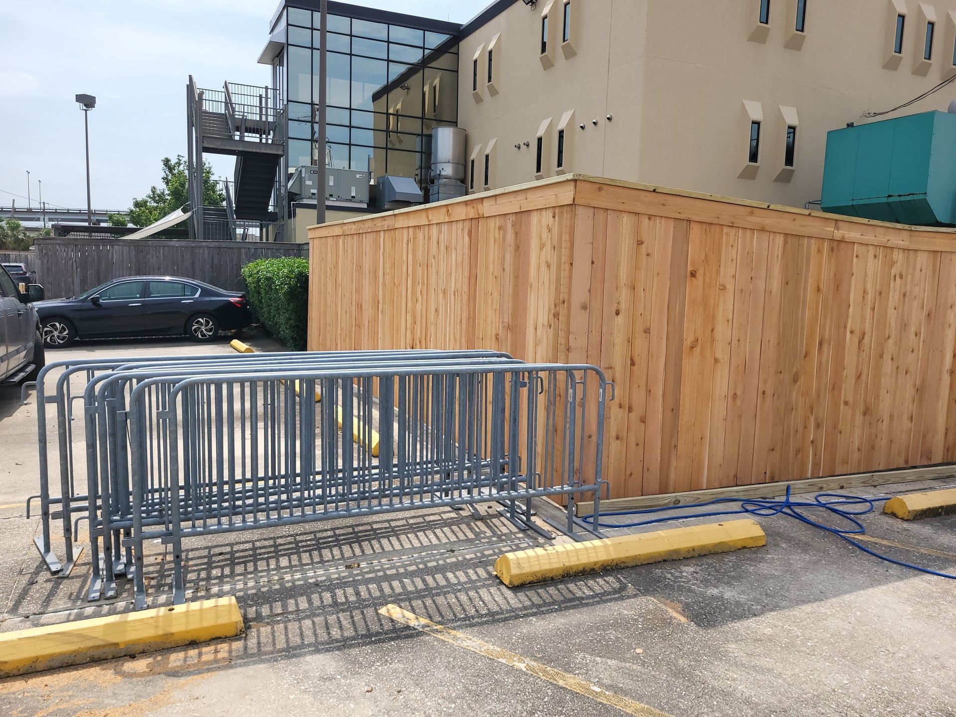 A wooden fence is being built in a parking lot in front of a building.
