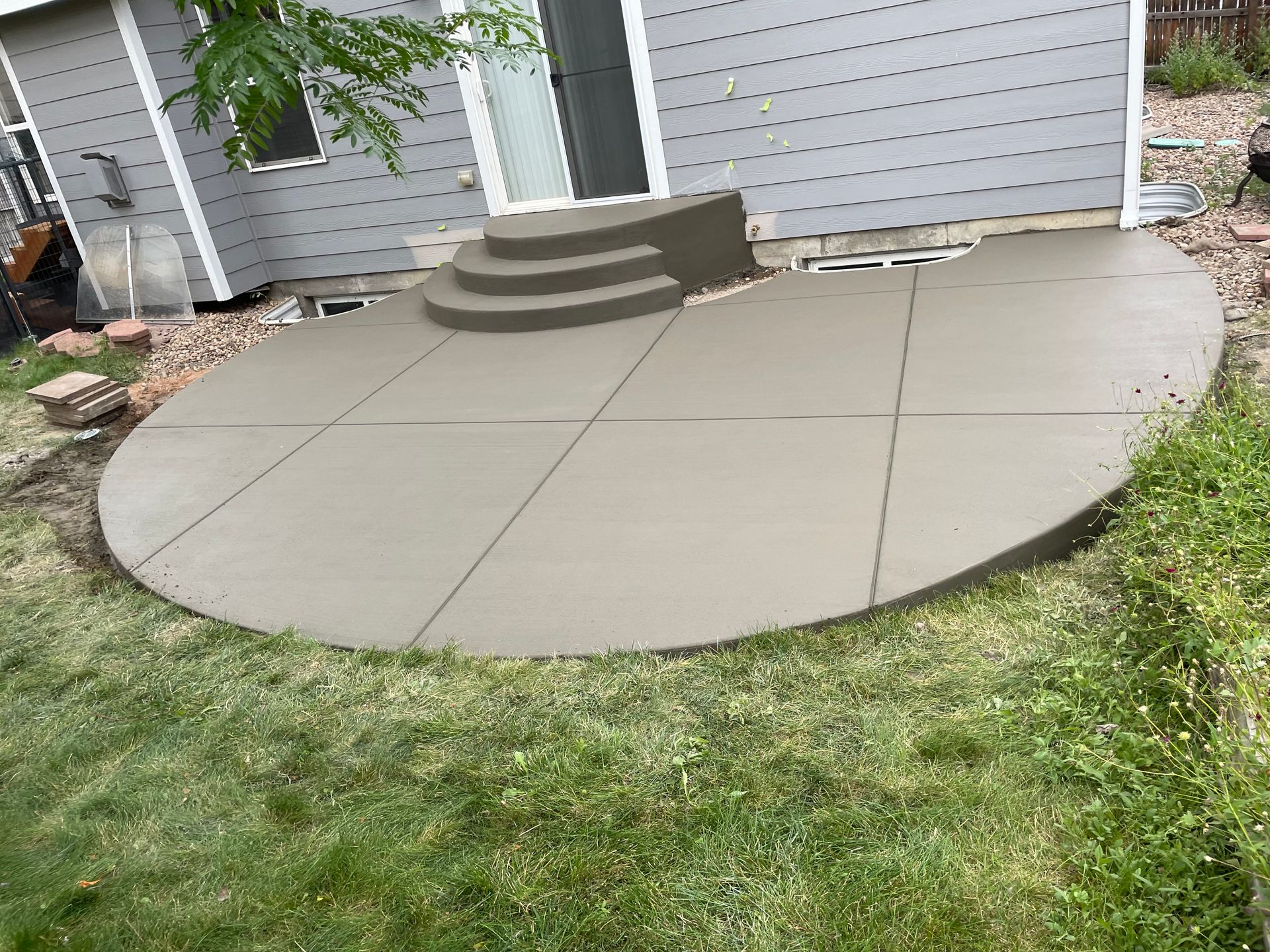 A concrete patio with stairs in front of a house.
